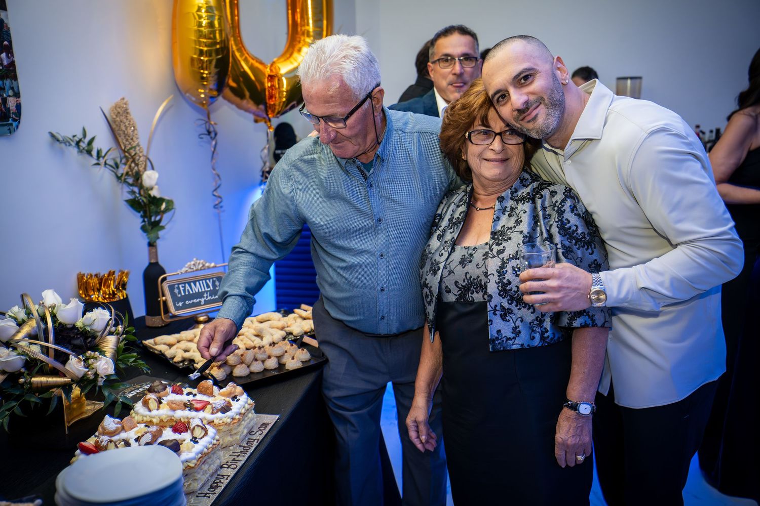 A group poses together near a dessert table with gold balloon decorations.