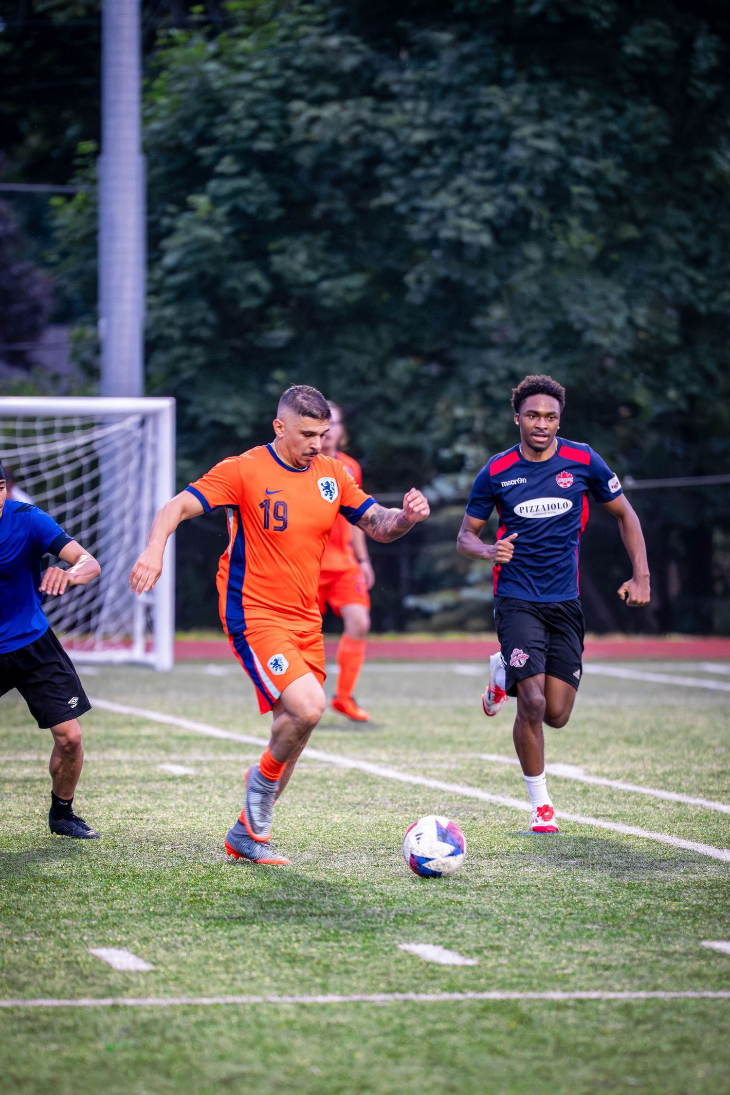 Players from opposing teams compete for possession of soccer ball during match.