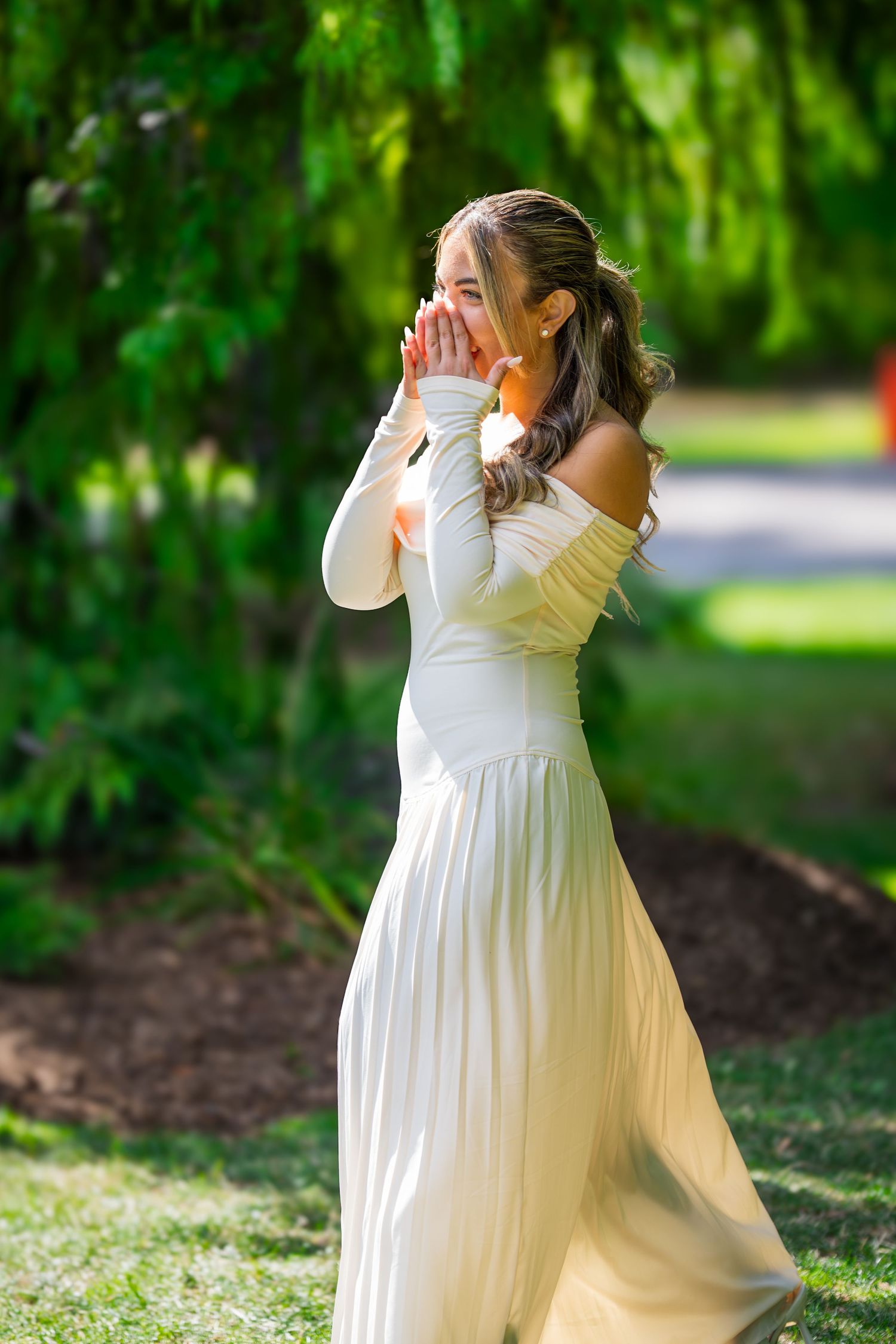 Woman in flowing white dress twirling joyfully in a garden setting.