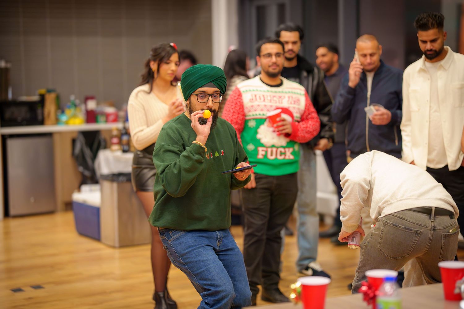Party guests watching and participating in holiday games with red cups.