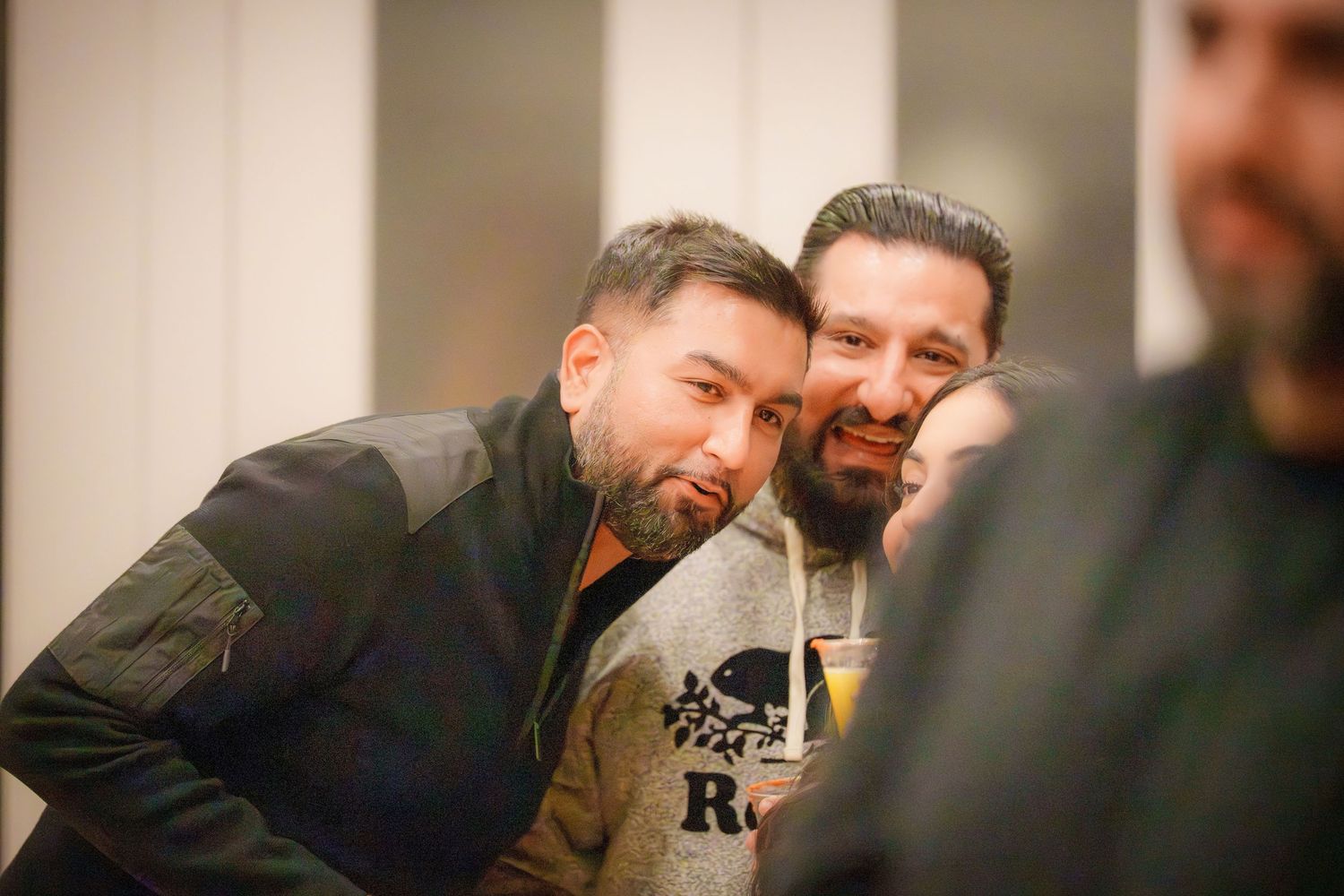 A group of people enjoying drinks and conversation at a casual indoor gathering.