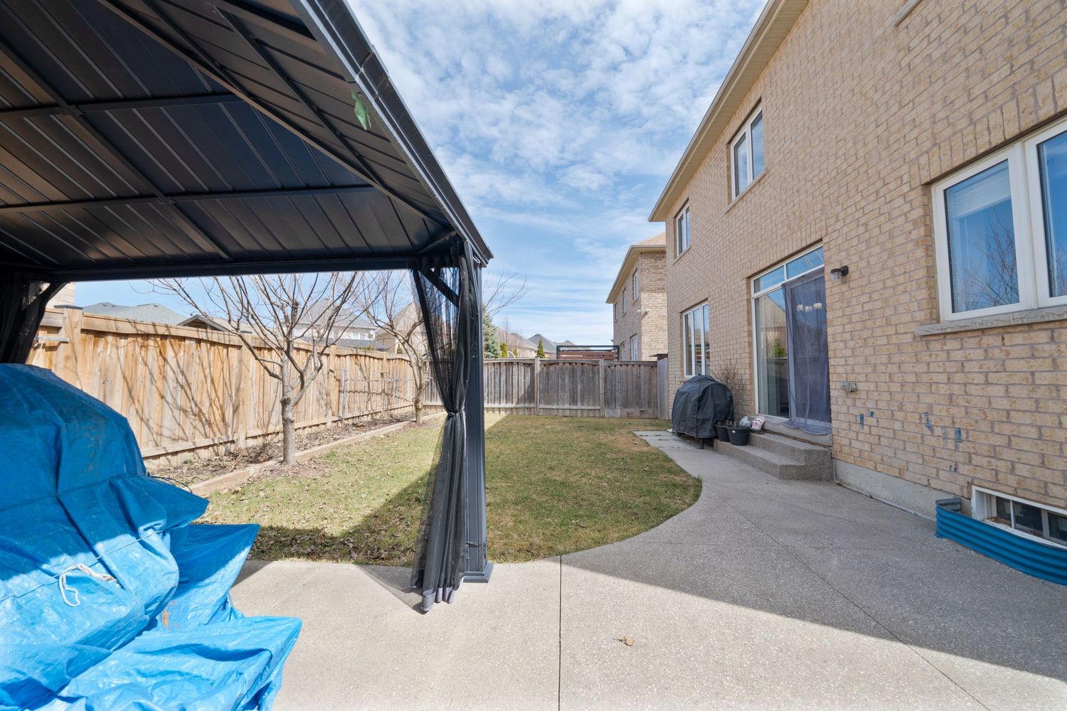 Panoramic view of a modern residential building exterior with beige brick walls and black awnings under a cloudy sky.