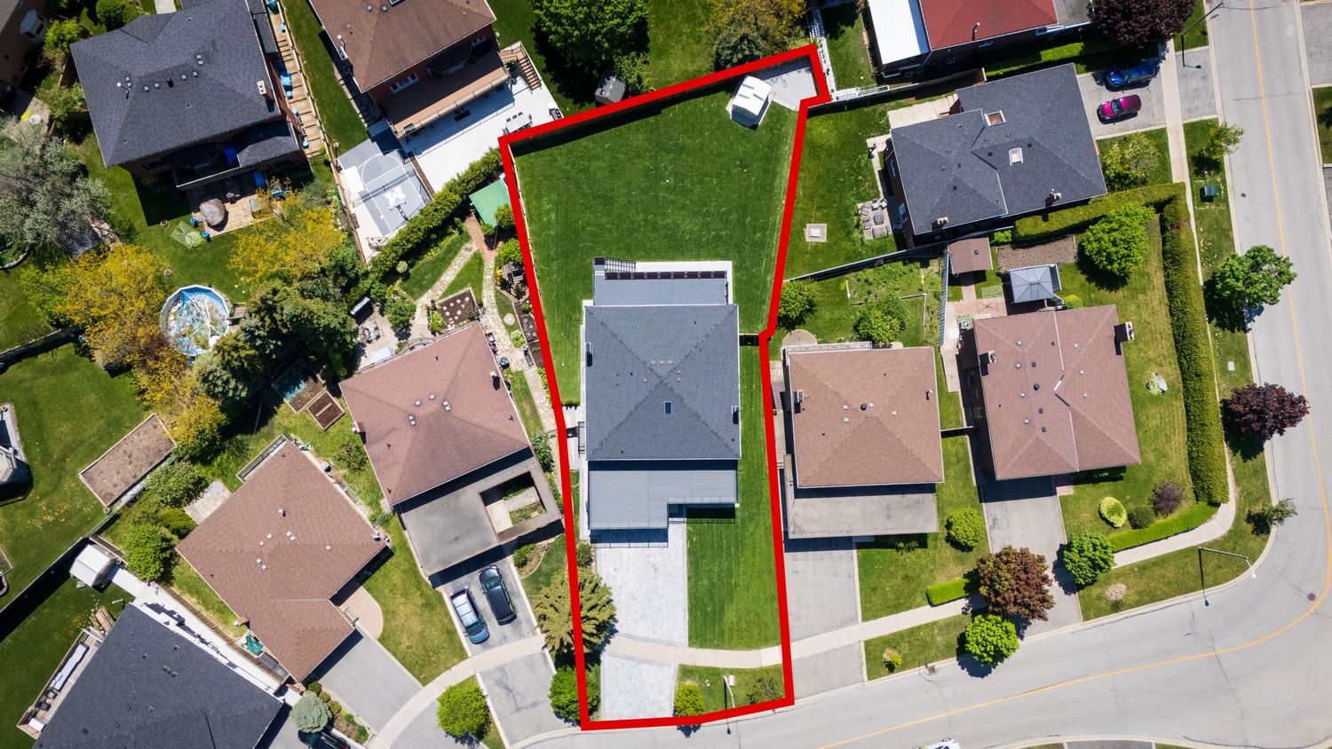 Aerial drone view of residential homes with a highlighted property boundary line marked in orange and red.