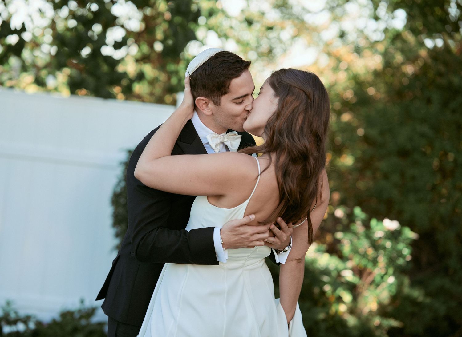 Nelstudios photographs a Jewish Wedding at The Inn at Longshore, Connecticut where the bride and groom kiss each other during romantics.