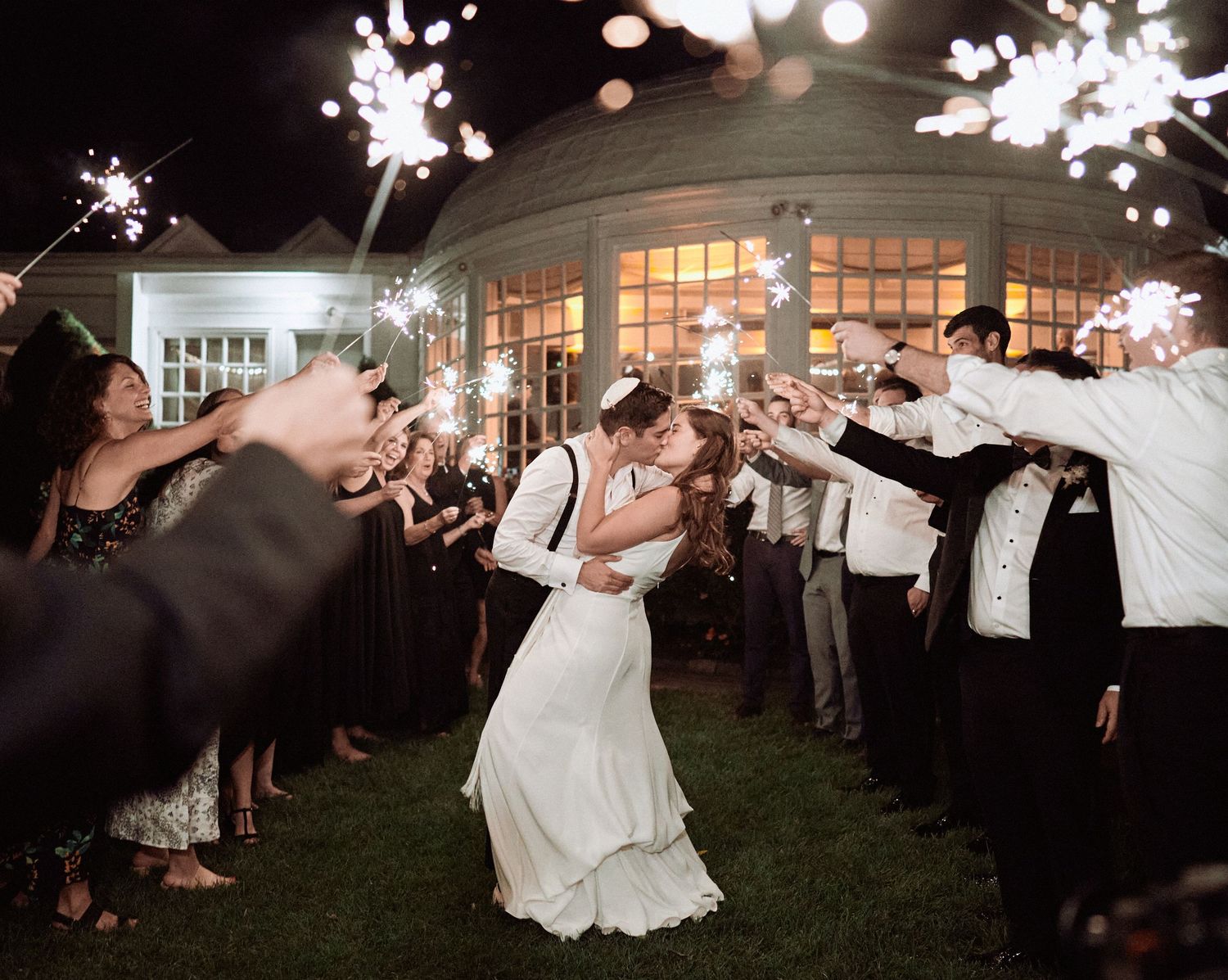Nelstudios photographs a Jewish Wedding at The Inn at Longshore, CT, USA where the bride and groom kiss while surrounded by sparklers.