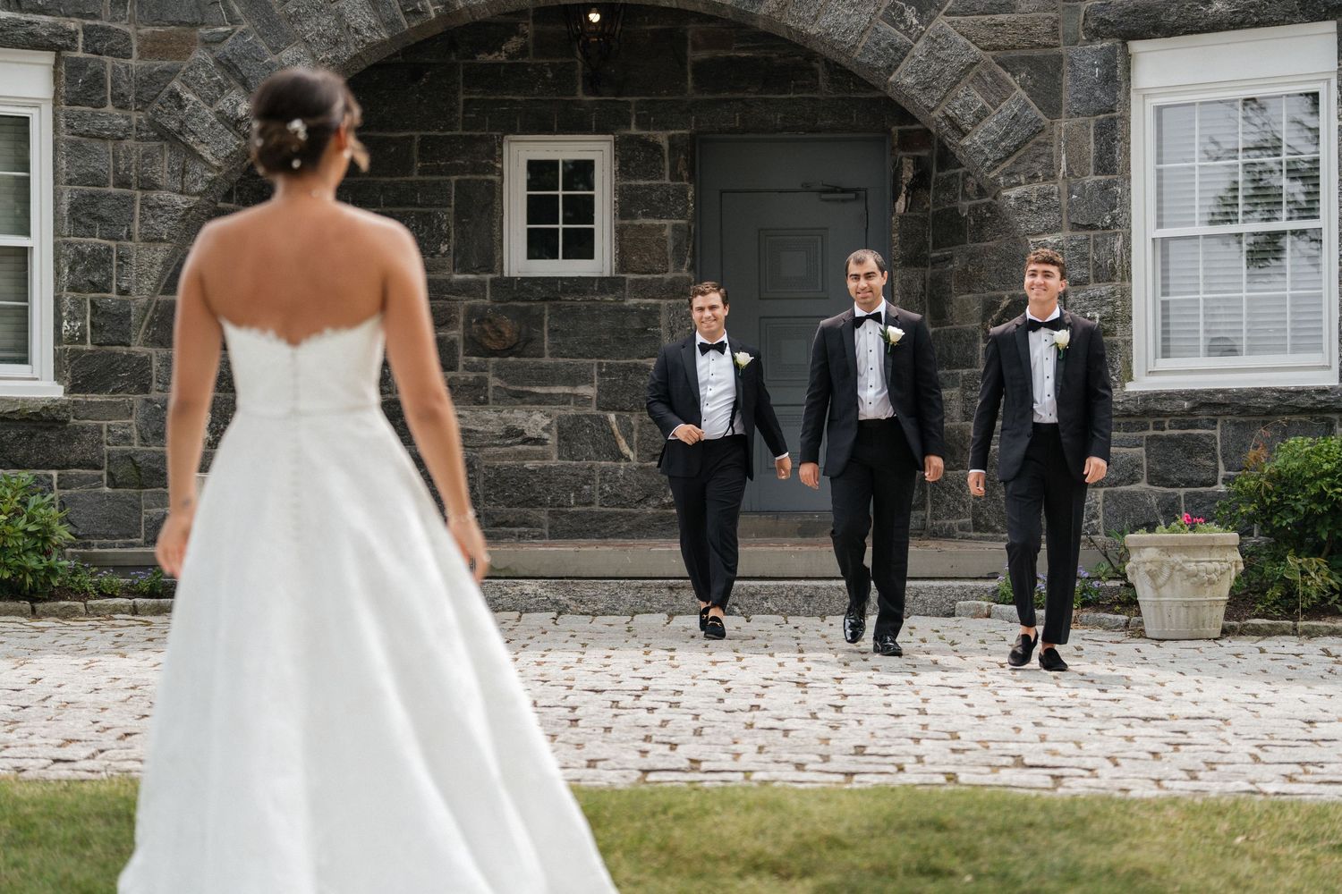 Nelstudios captures a natural, candid moment of the bride embracing her brothers at Whitby Castle, Rye, Westchester, NY.