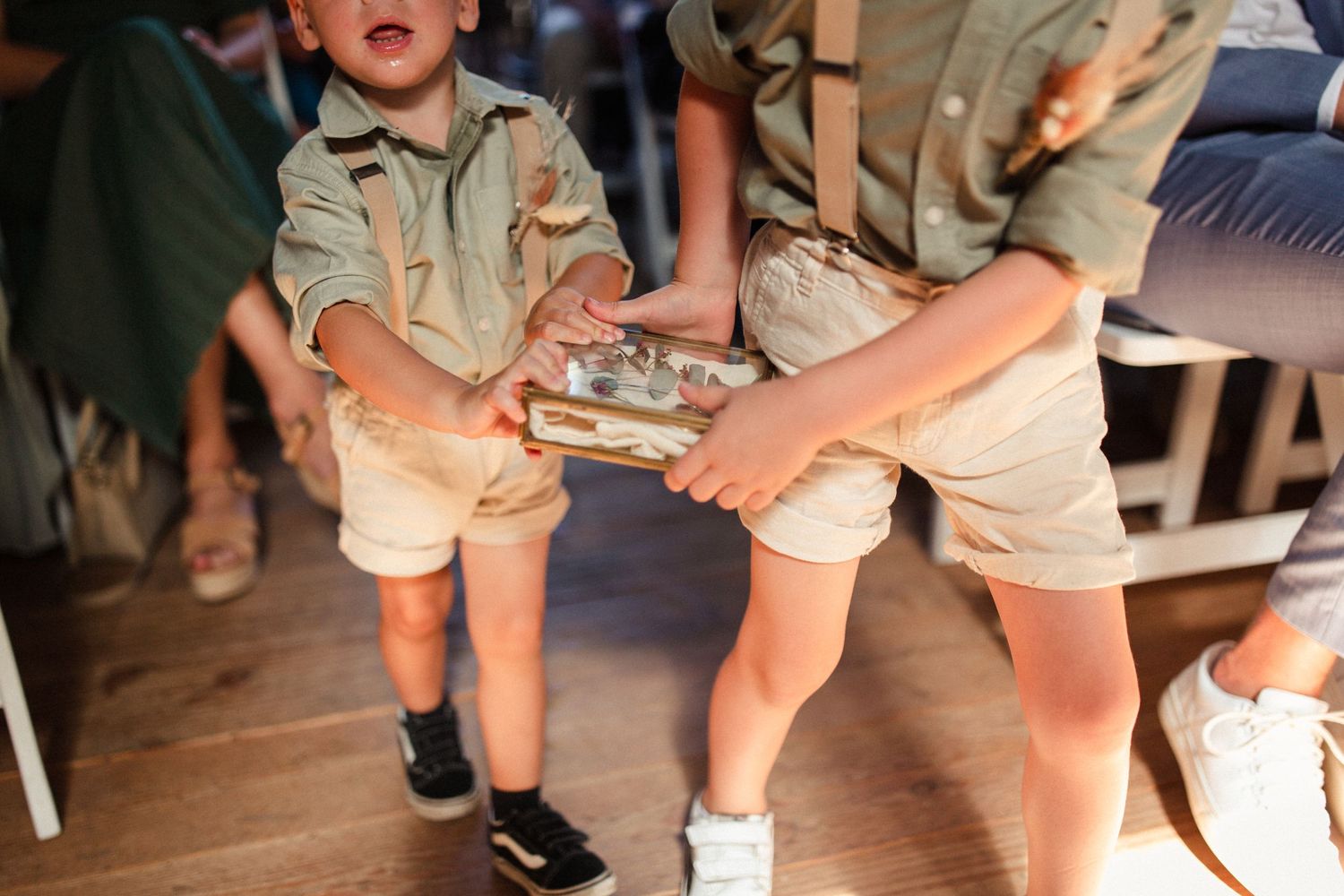 Children in casual khaki outfits dance together on a wooden floor during a party gathering.