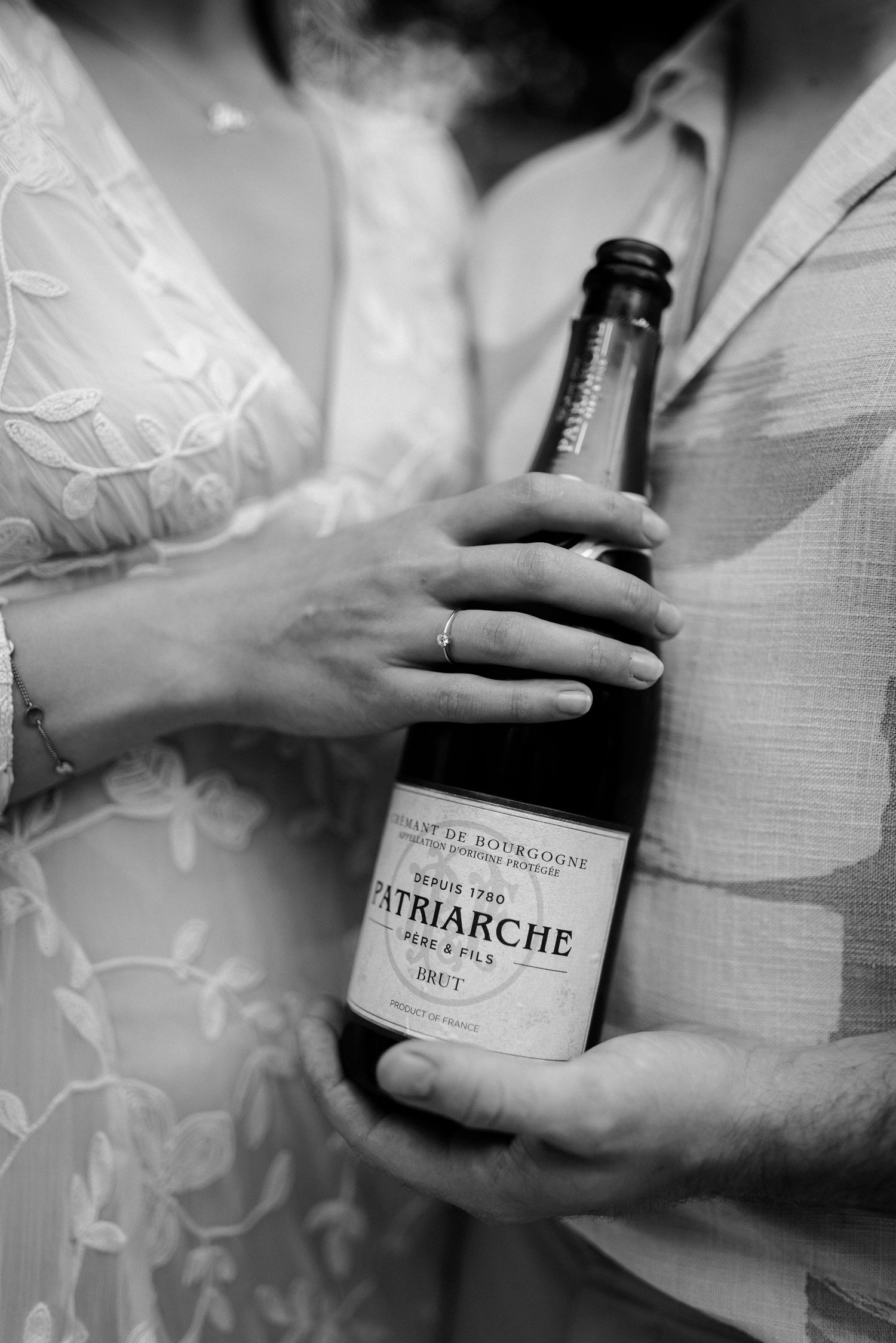 Fles champagne in de handen van een koppel.