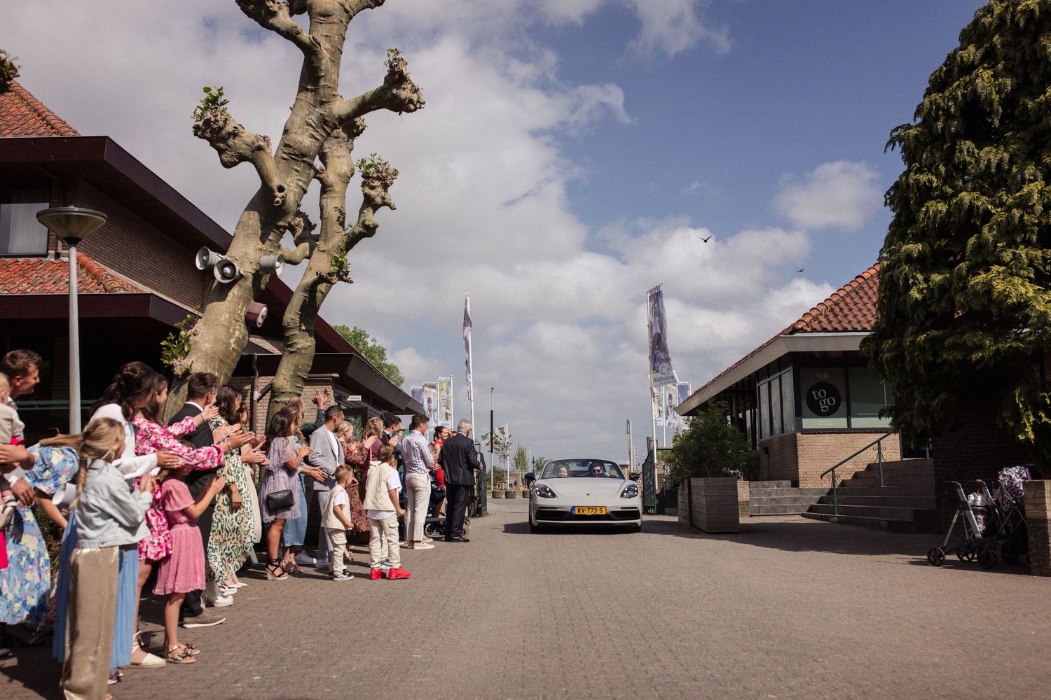 A crowd of wedding guests line a brick street with the Eiffel Tower visible in the distance.