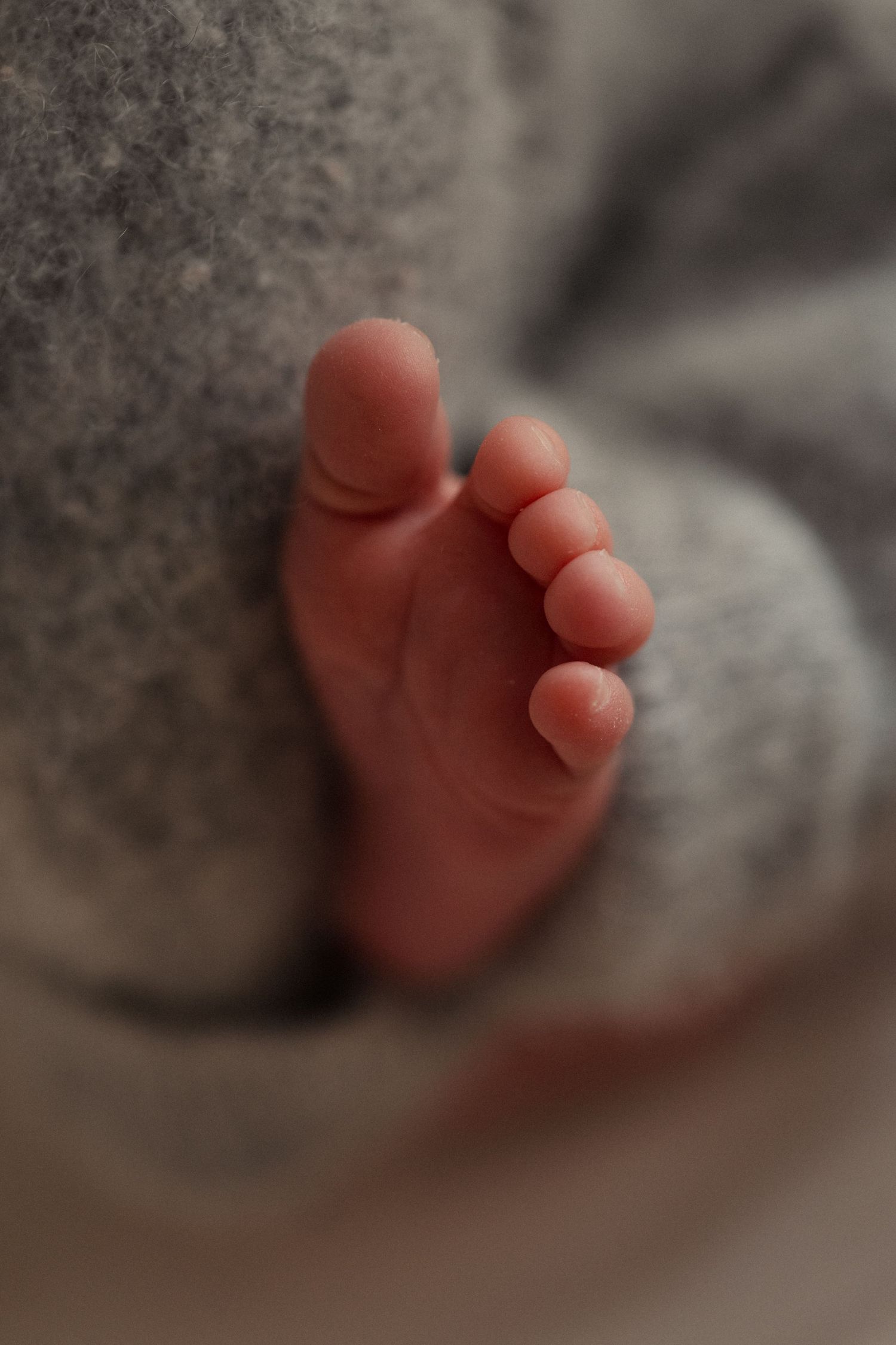 Een close up foto van een babyvoetje en een beetje wollen stof van het babybroekje