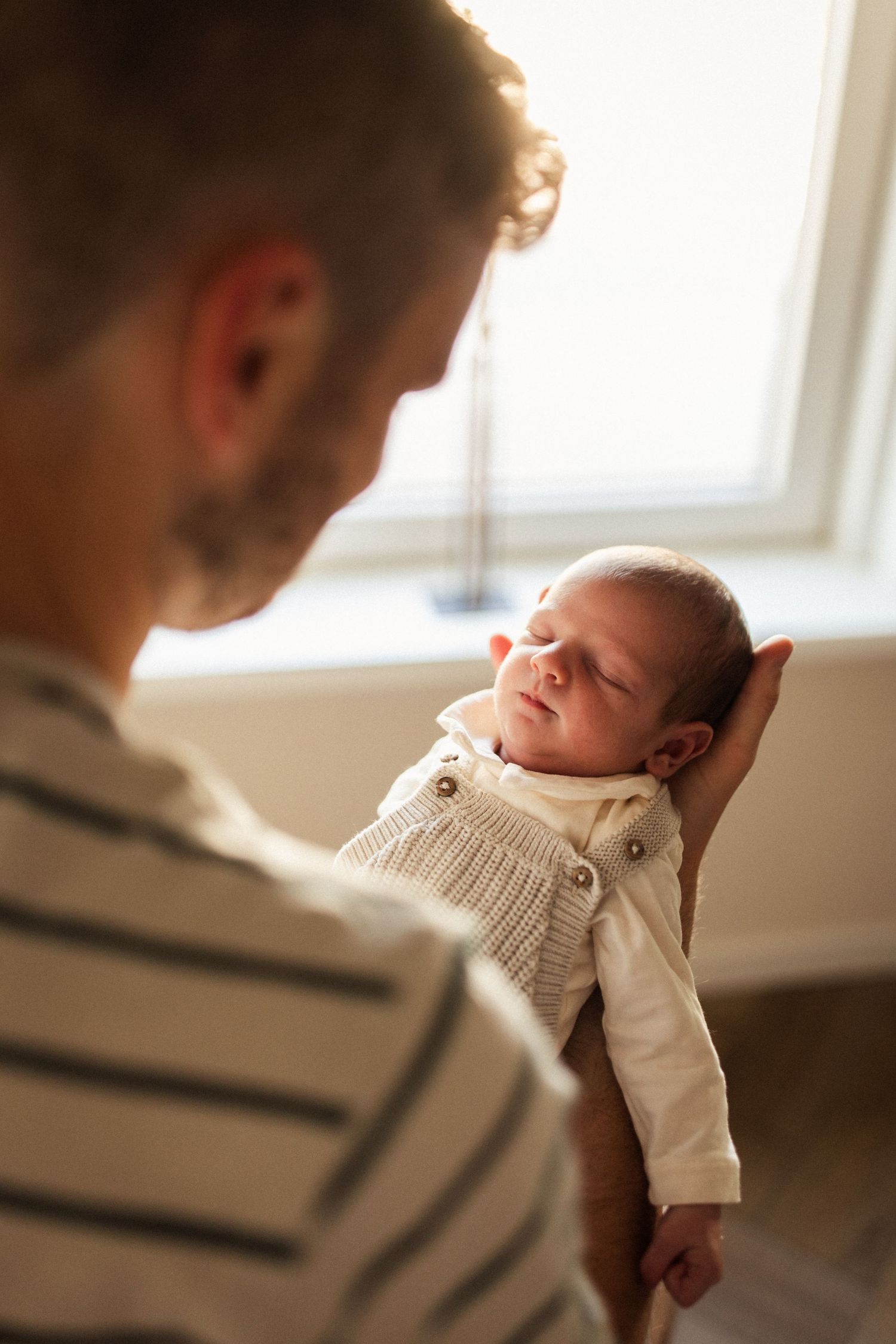 Vader houd baby voor zich in zijn armen.
