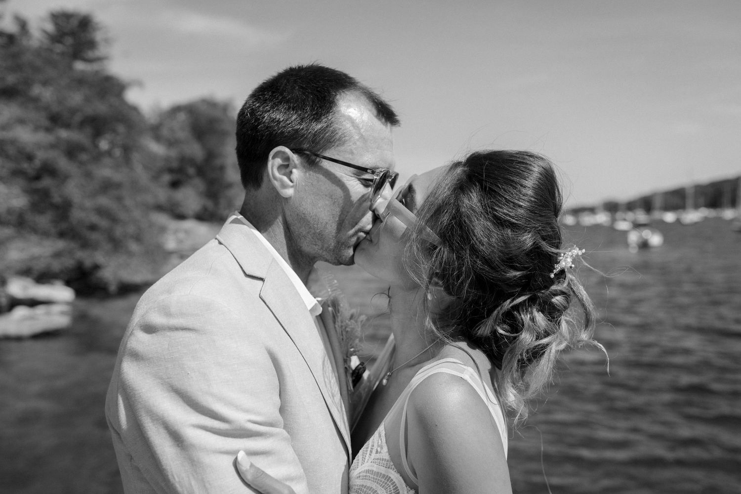 An intimate black and white wedding photo of a couple sharing a moment by the waterfront.