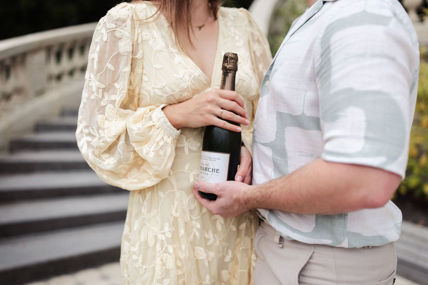 Een koppel in pasteltinten die een fles champagne vasthouden.
