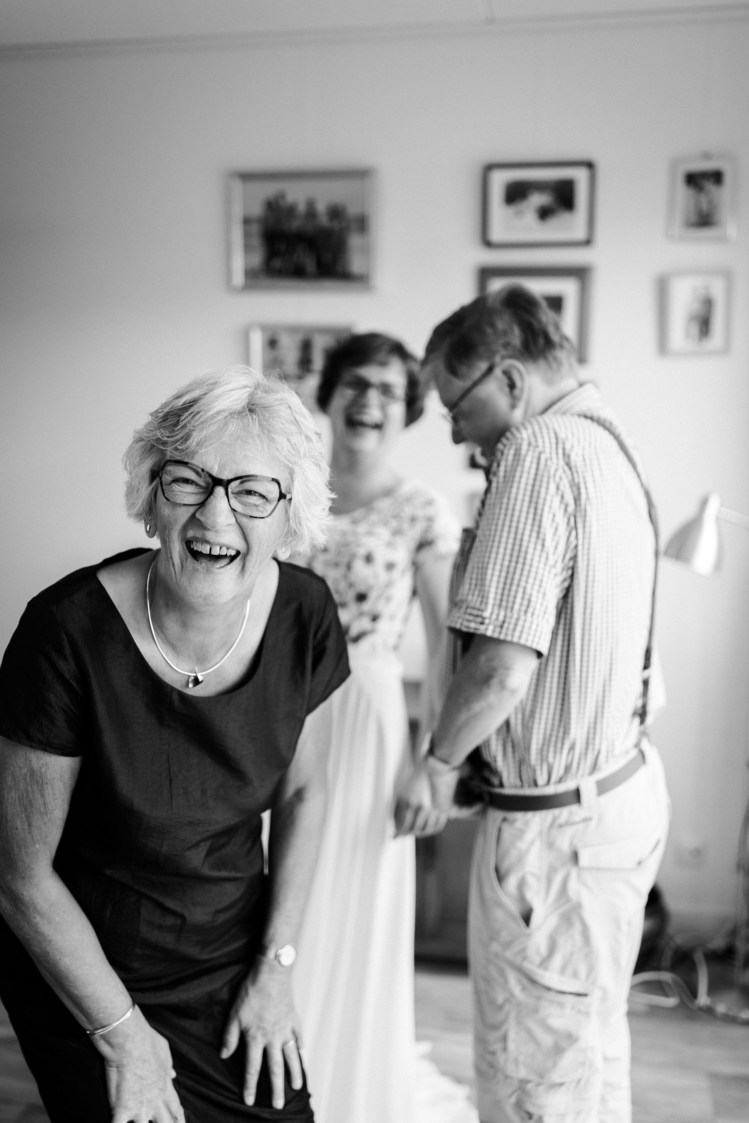 Bruid die samen met haar ouders hard lacht tijdens het klaarmaken.
