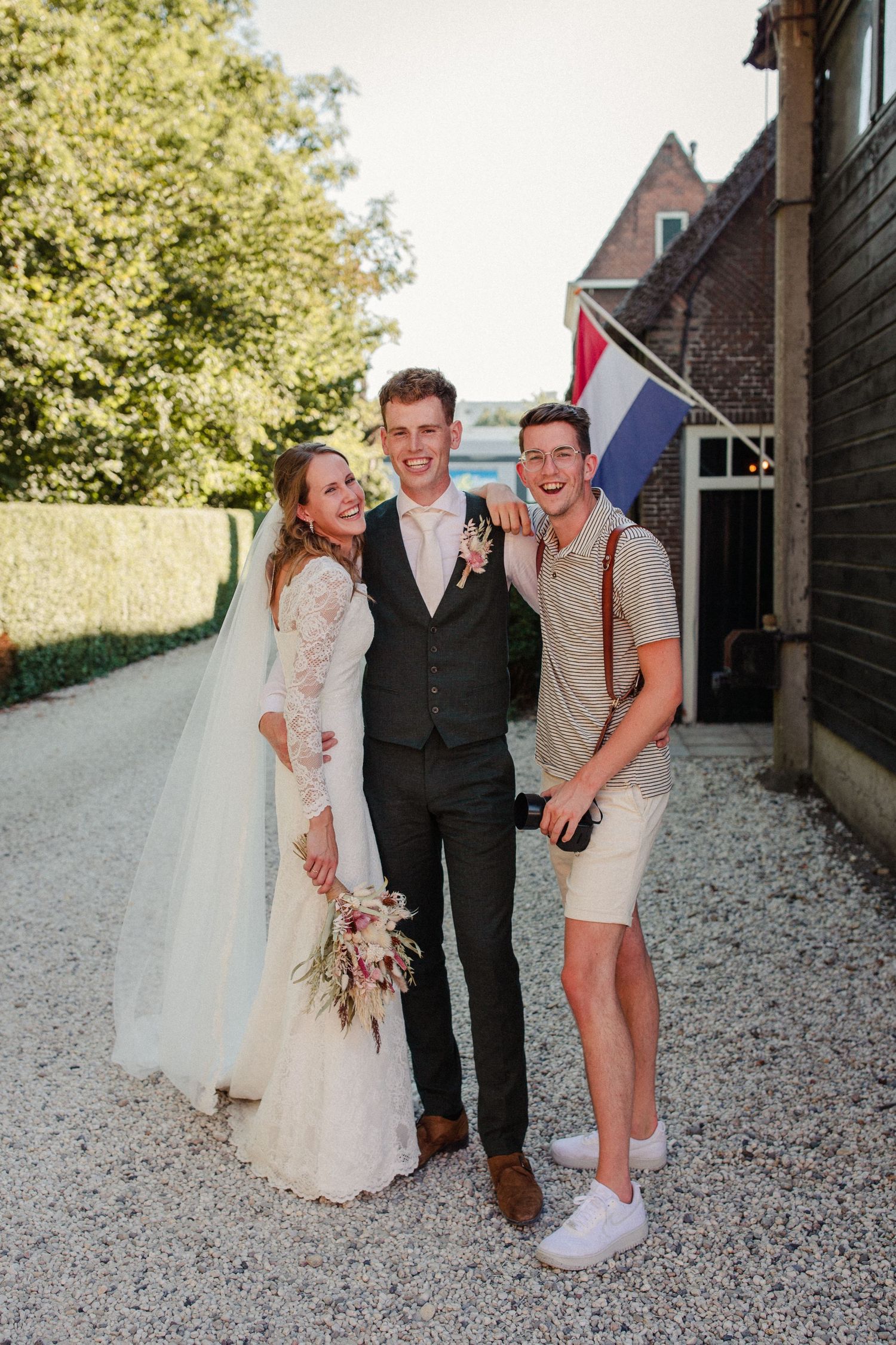 Celebratory gathering at outdoor wedding venue with Dutch flag in background on sunny summer day.