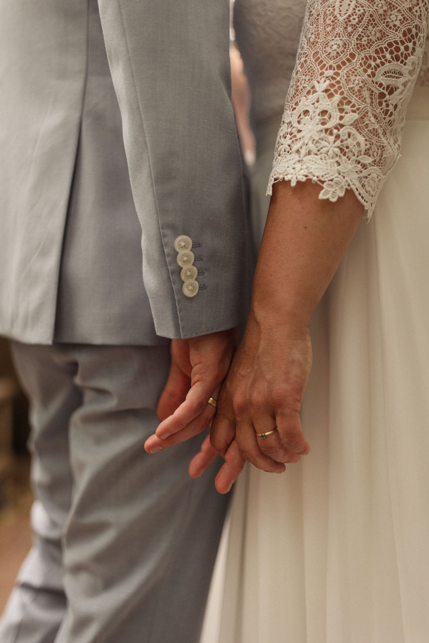 Close up shots of hands and formal attire showing grey suit pants next to white lace fabric.