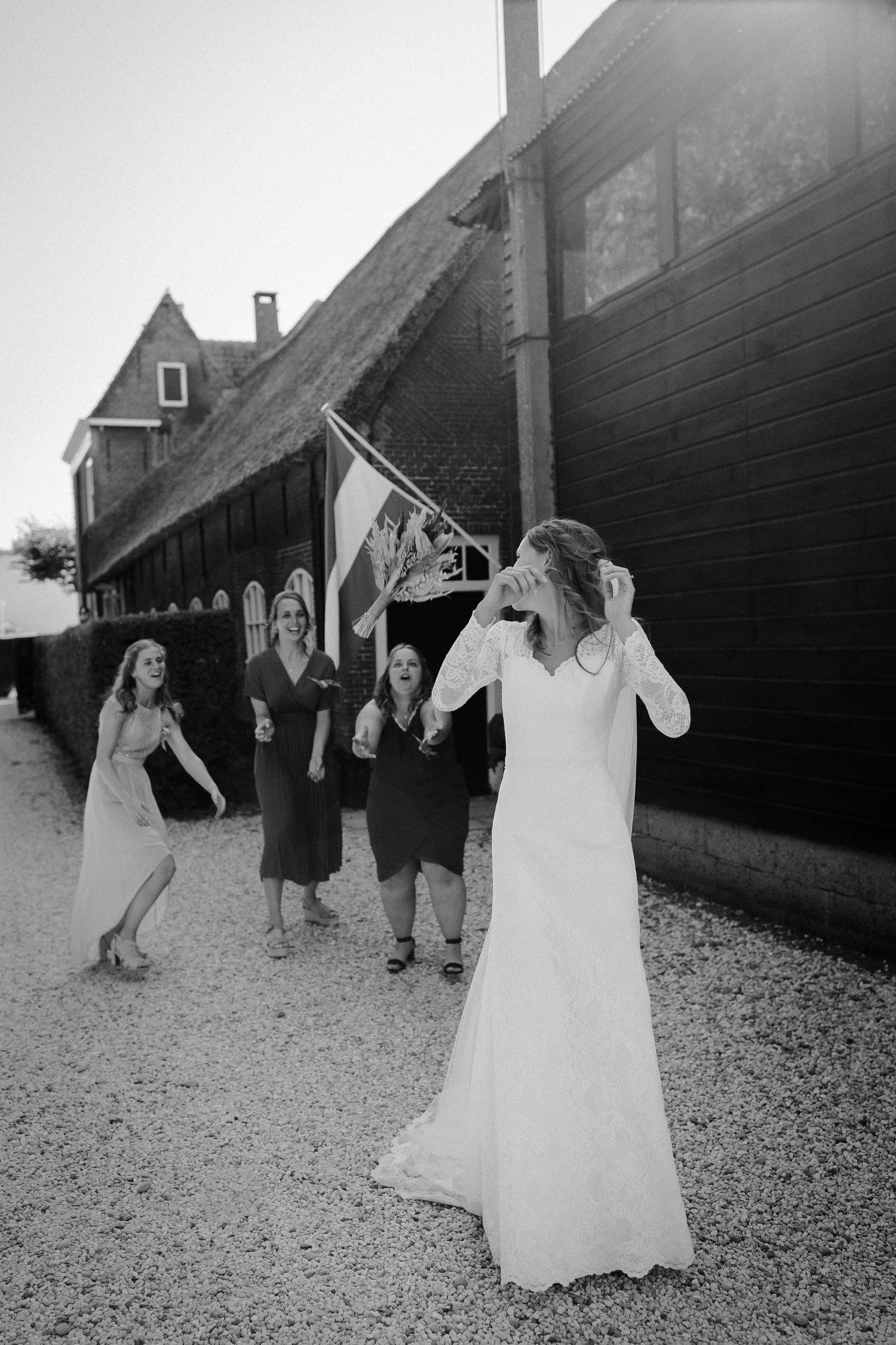 A wedding celebration scene outside a rustic barn with a person in white dress and guests celebrating.