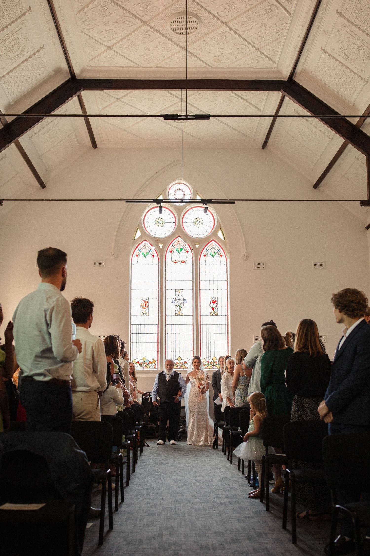 Wedding ceremony in a church with stained glass windows and vaulted ceiling.