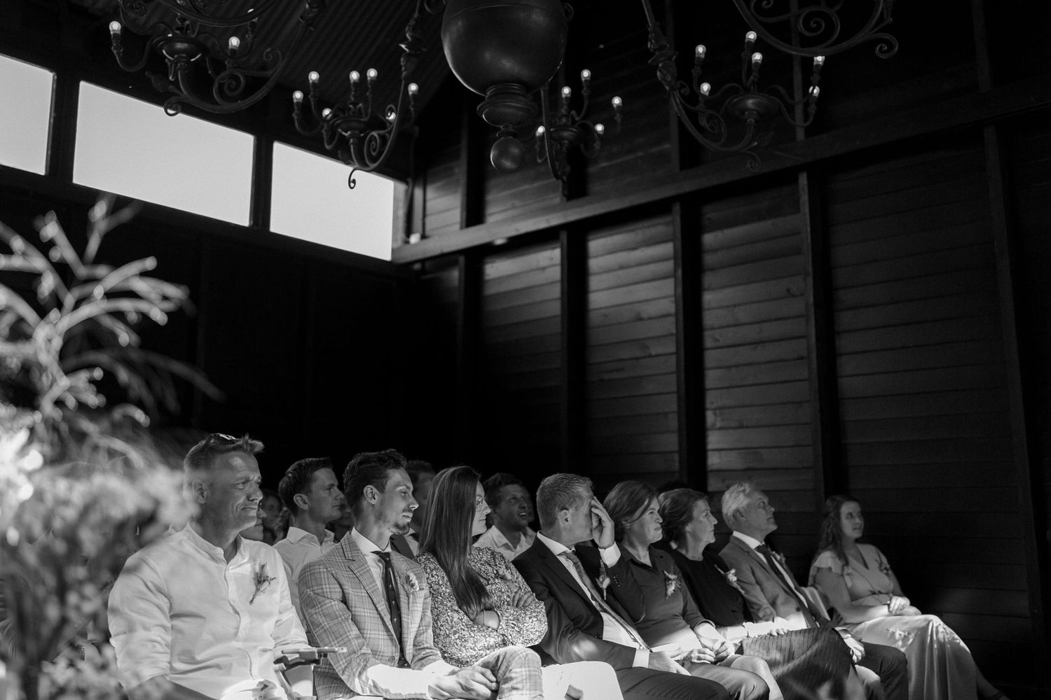 Audience members sitting in a row watching a performance in black and white photograph.