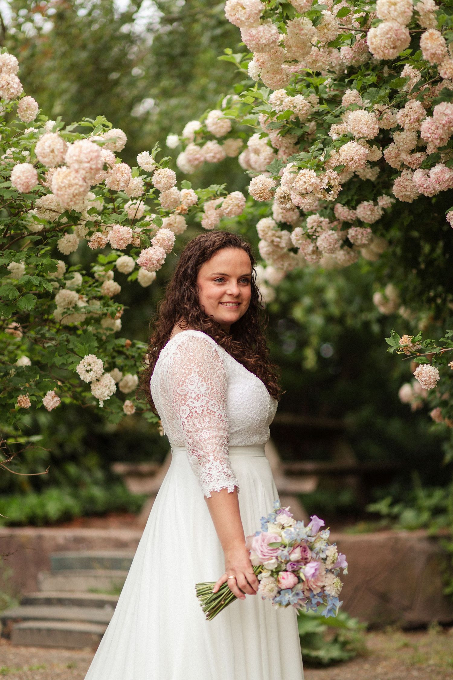 Beautiful wedding scene with white and pink roses blooming on elegant garden arbor.