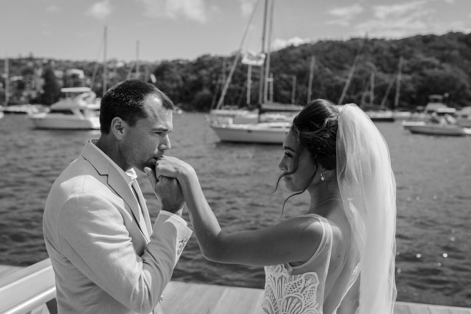 A black and white wedding photo capturing an intimate moment on a marina dock.