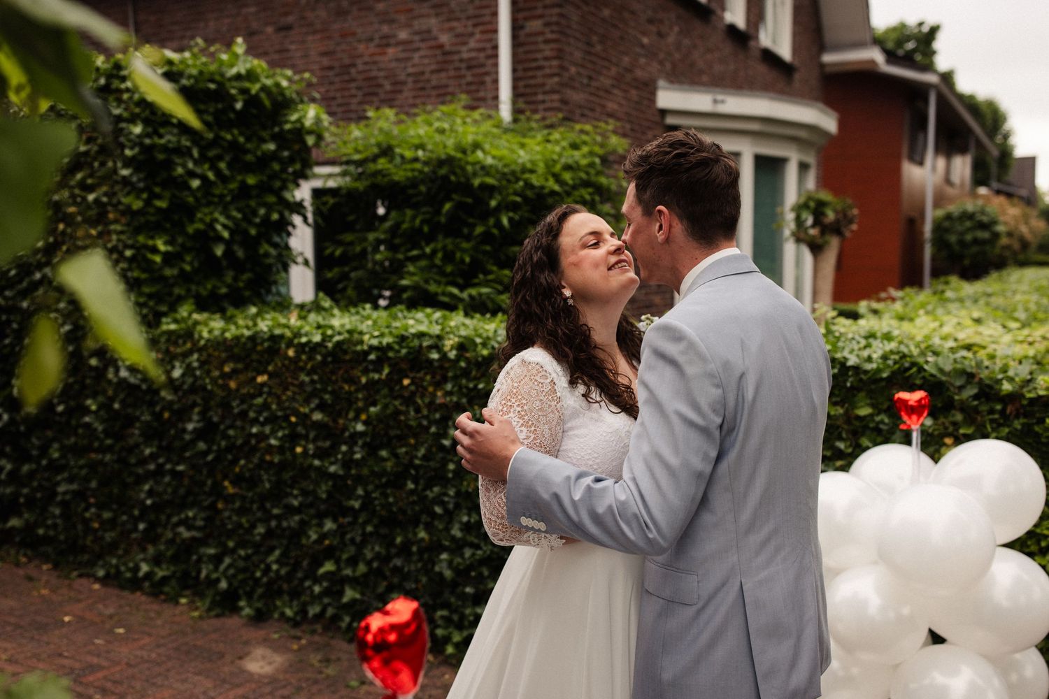 Newlyweds celebrate in garden setting with white balloon decorations.