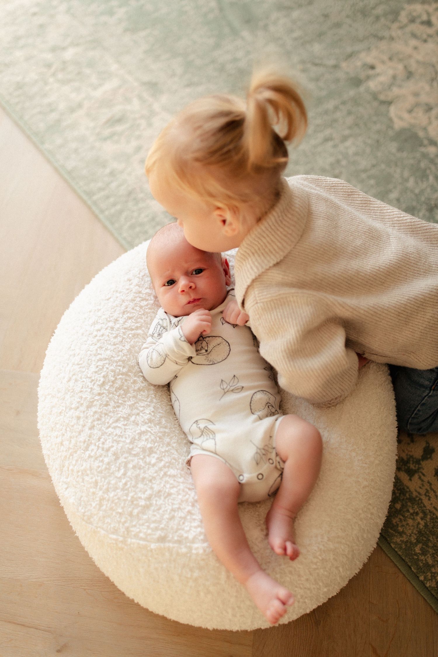 Meisje die haar baby broertje een kusje geeft op zijn voorhoofd.