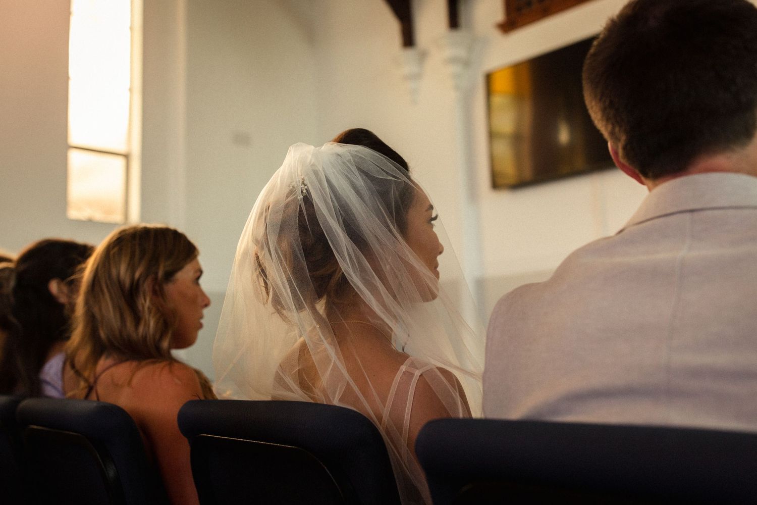 Wedding attendees seated in church pews during ceremony.