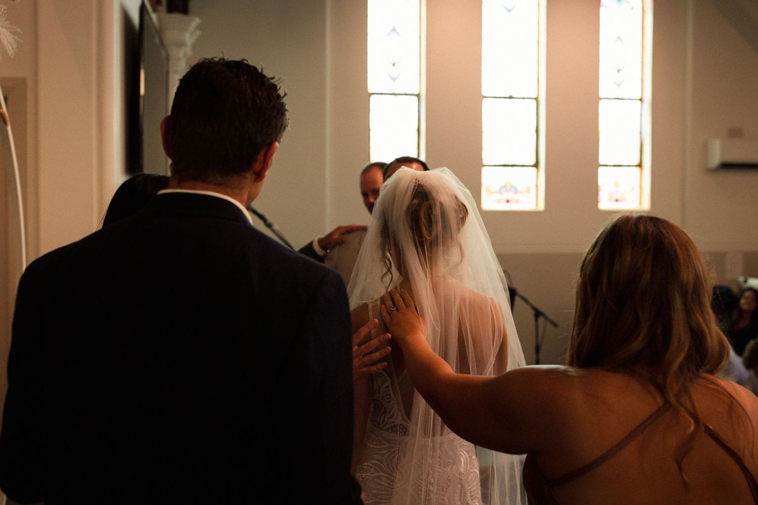 Wedding ceremony in a church with sunlight streaming through stained glass windows.