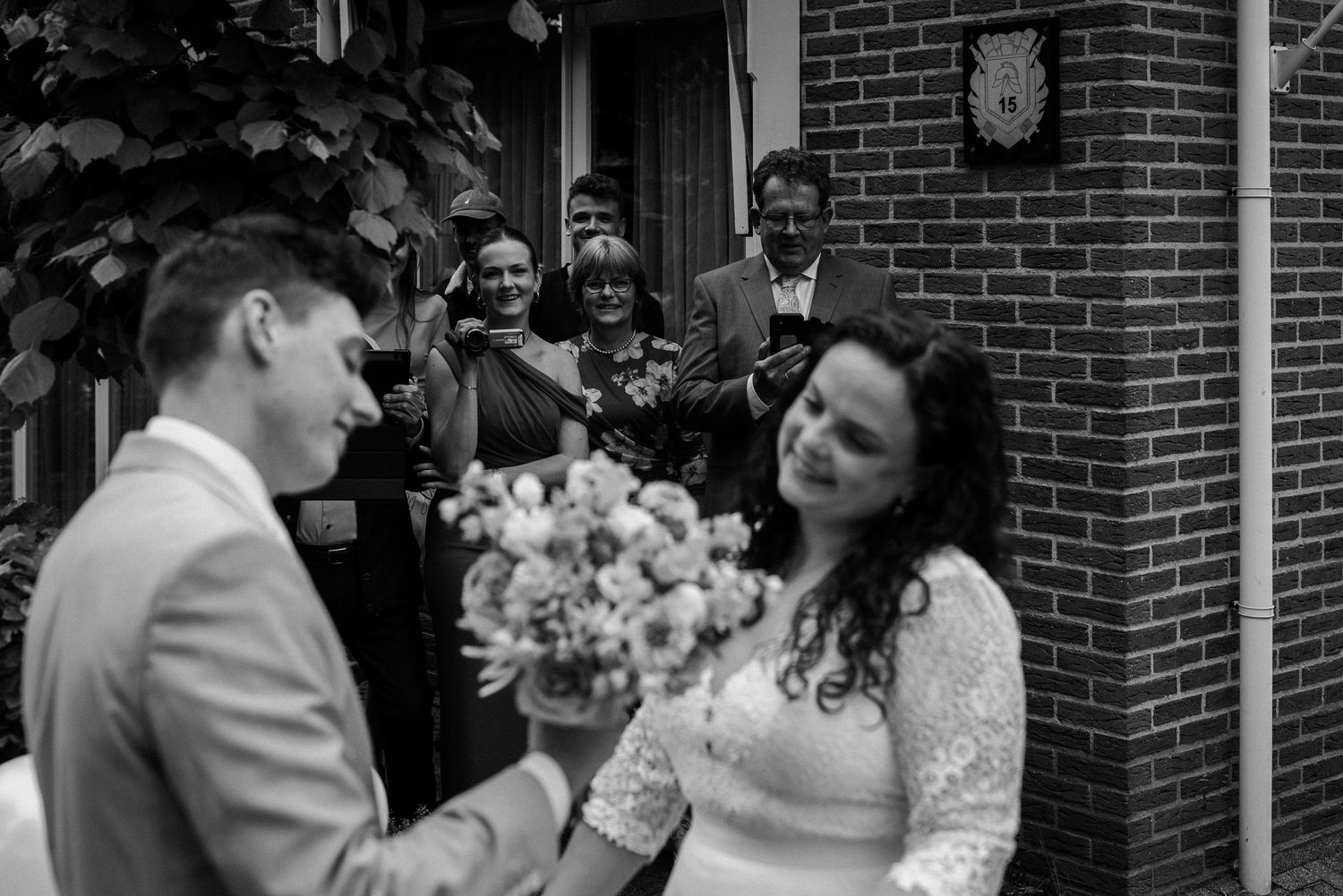 Bruid en bruidegom tijdens de first look. Op de achtergrond zie je familie als toeschouwers.