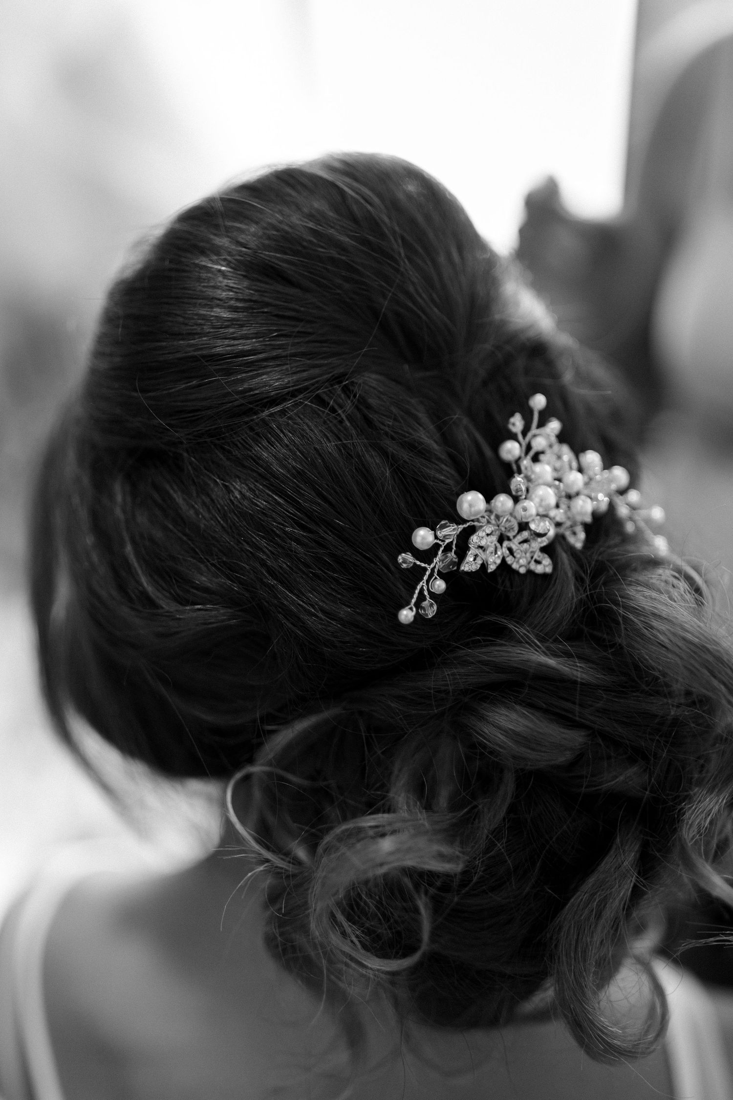 Black and white photo of an elegant pearl hair accessory in an updo.