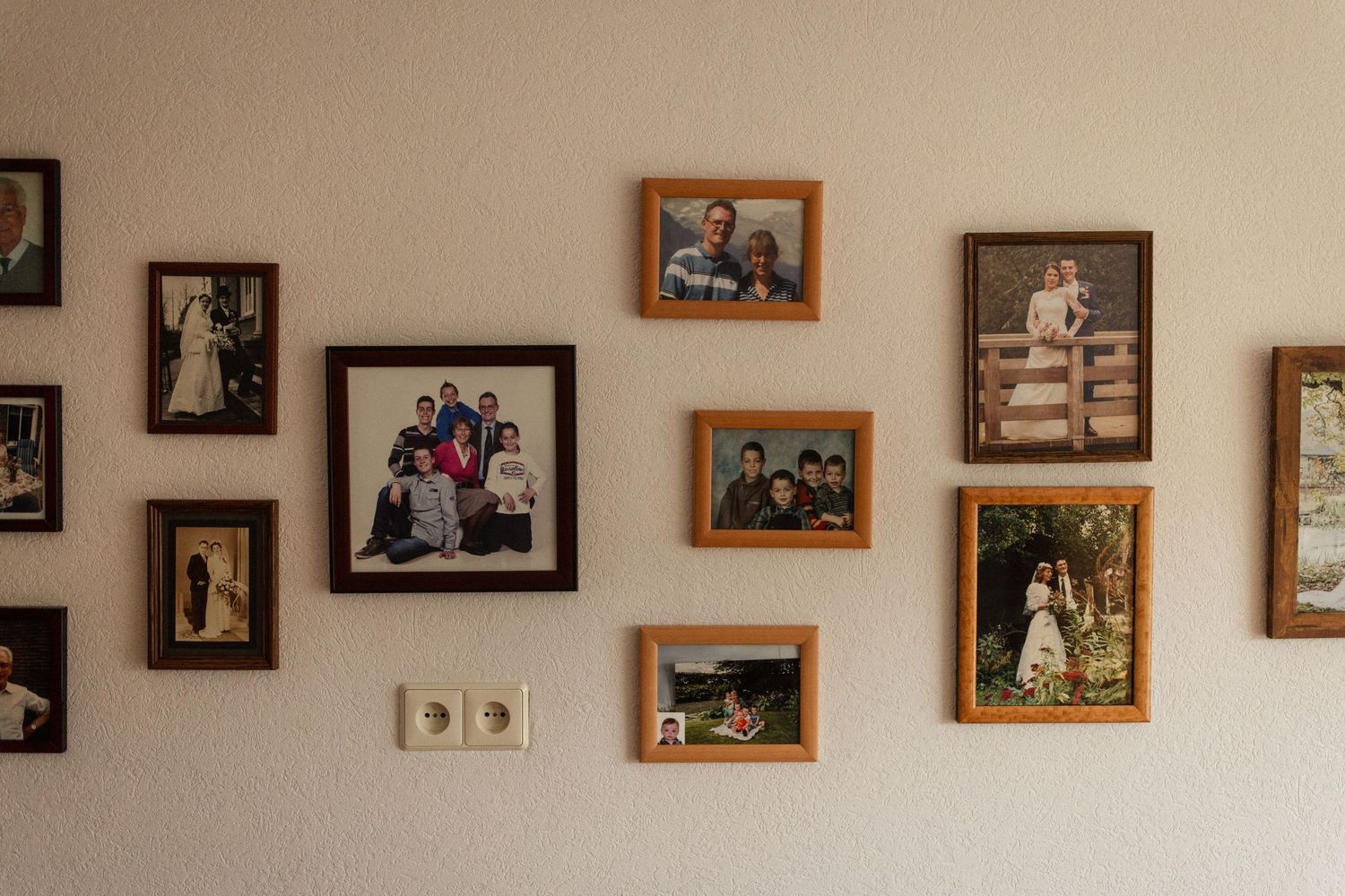 Collection of family photographs displayed on a wall in vintage wooden frames.