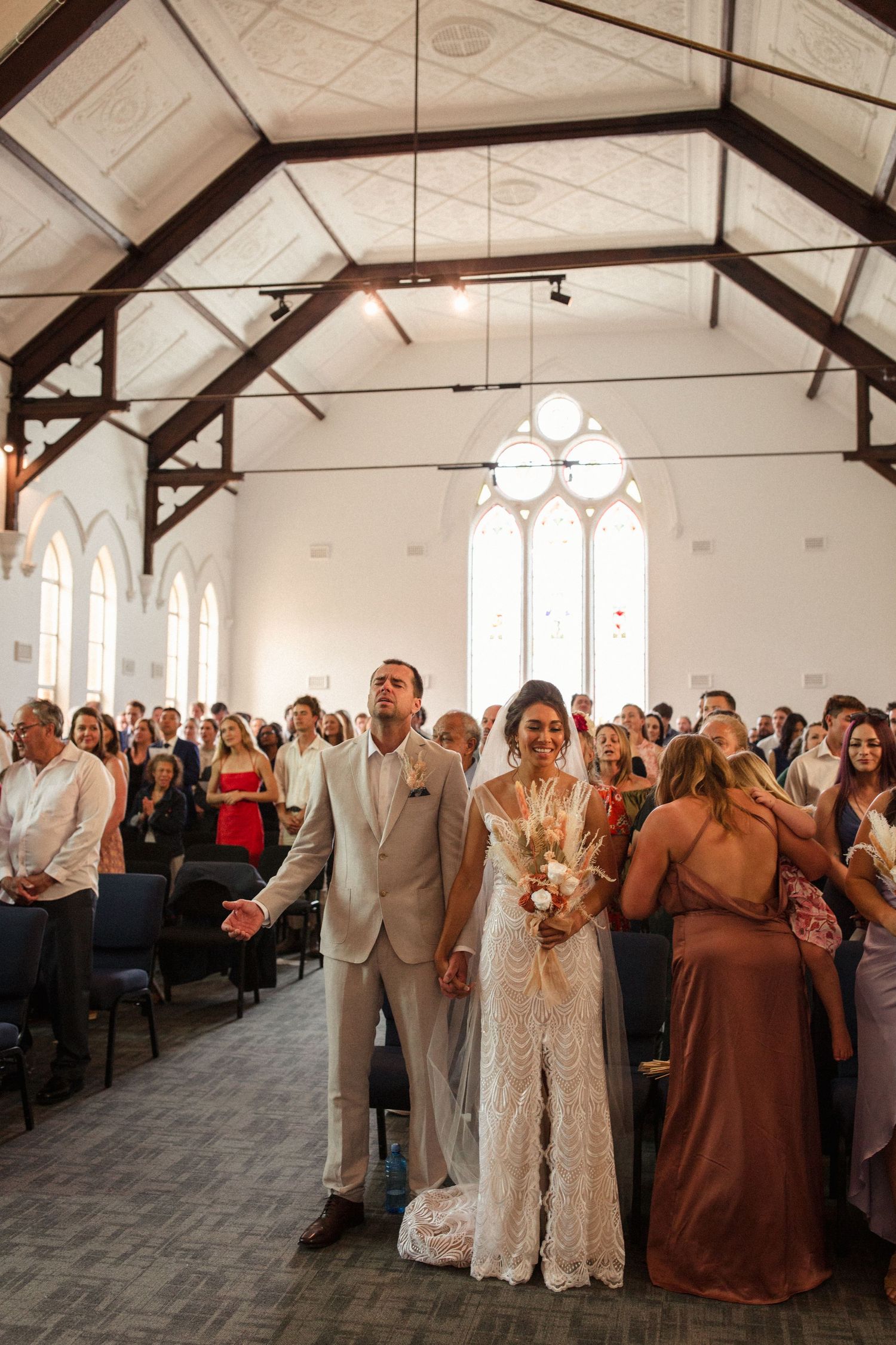 Wedding celebration in a church with exposed wooden beams and arched windows.