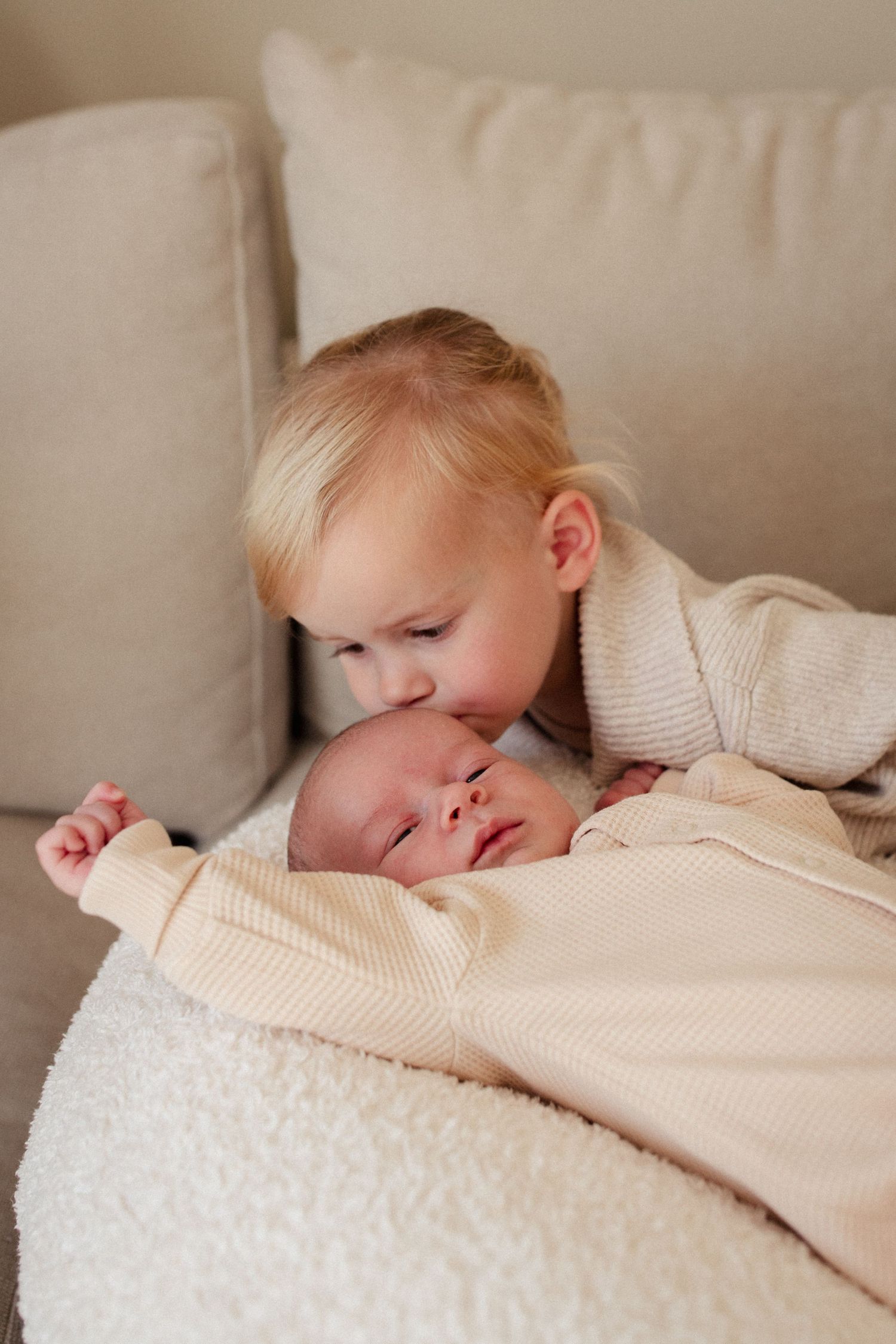 Tender moment between siblings on comfortable couch.