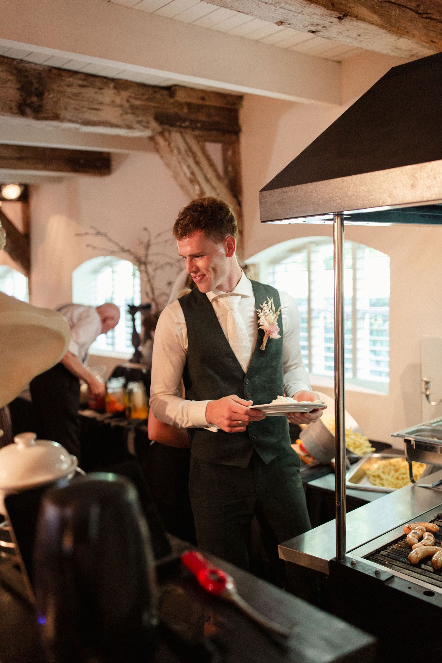 A formally dressed server checks an order while standing at a food service station with warming lamps.