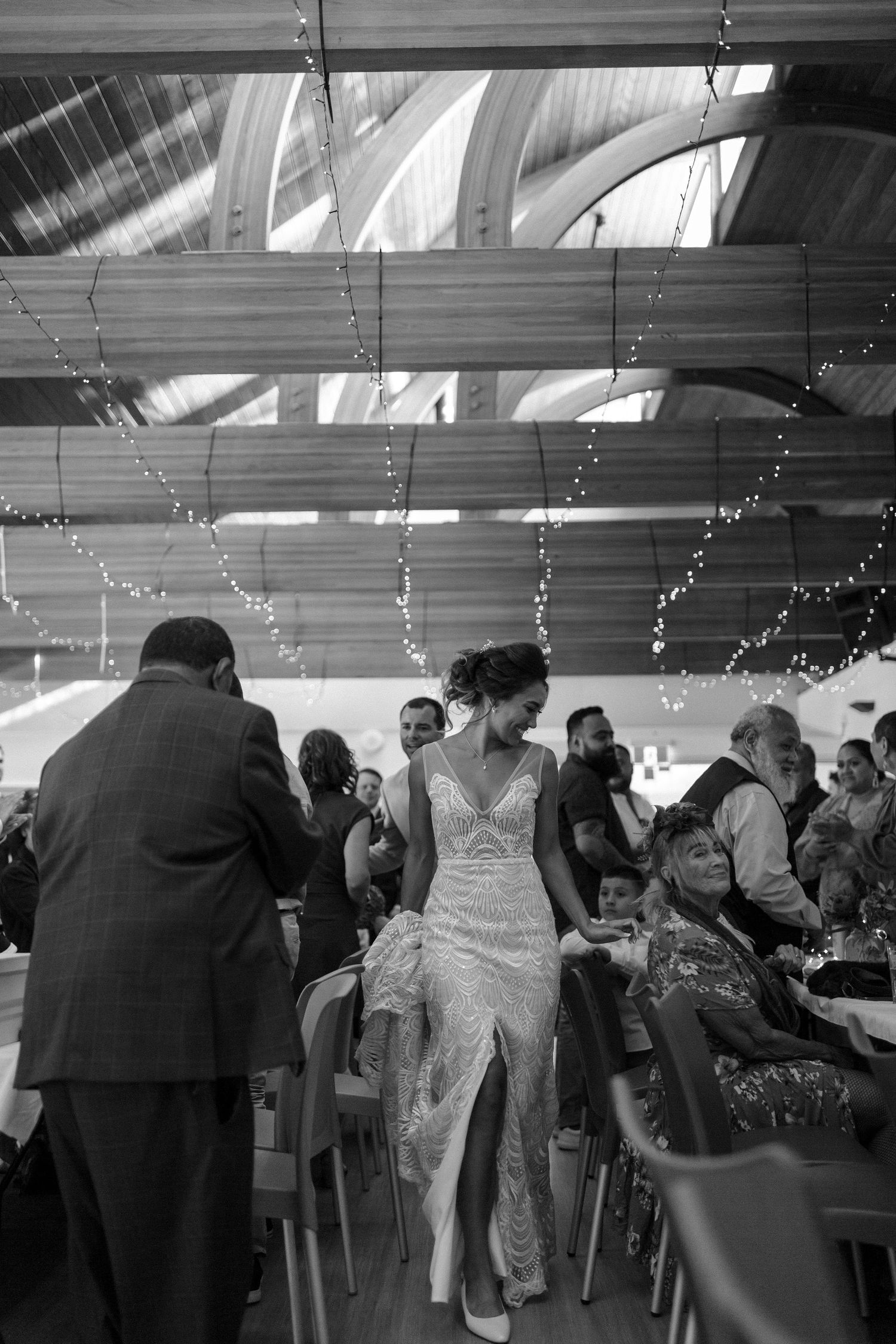 A black and white reception scene with fairy lights and wedding guests enjoying the celebration.