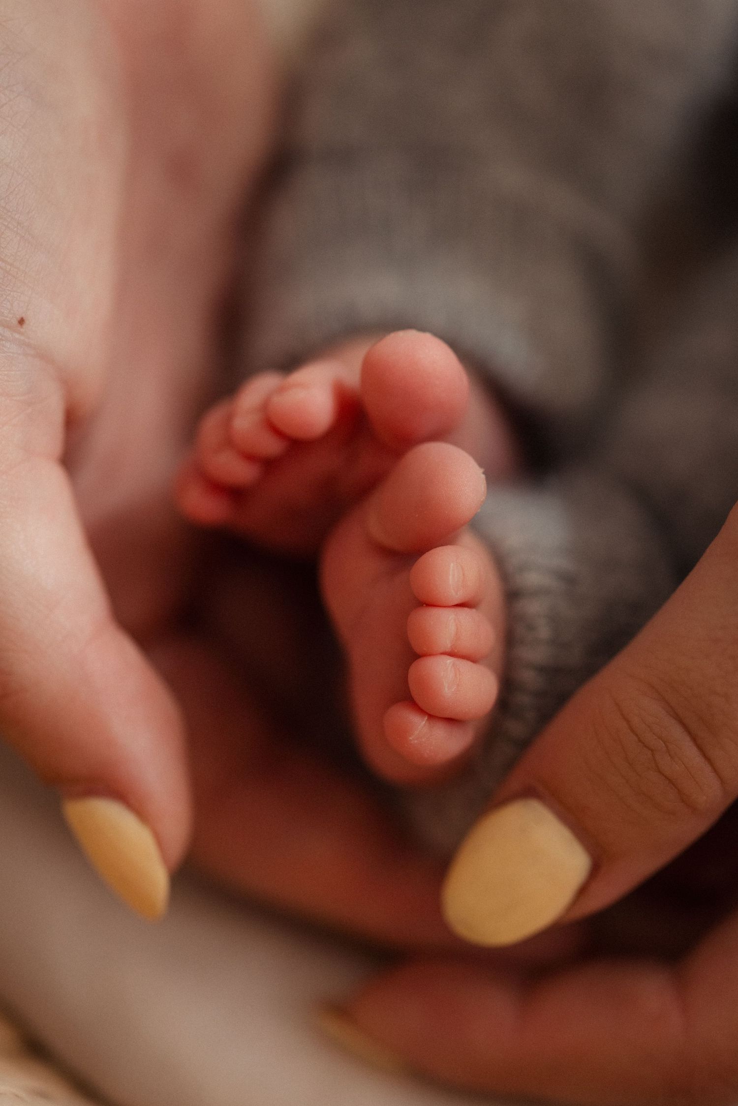 De handen van mama die piepkleine baby voetjes vasthoudt.