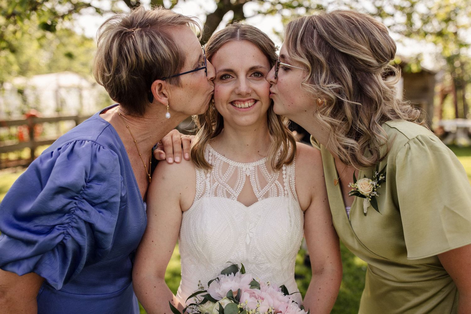 Emotional moment between bride and loved ones in a garden setting.