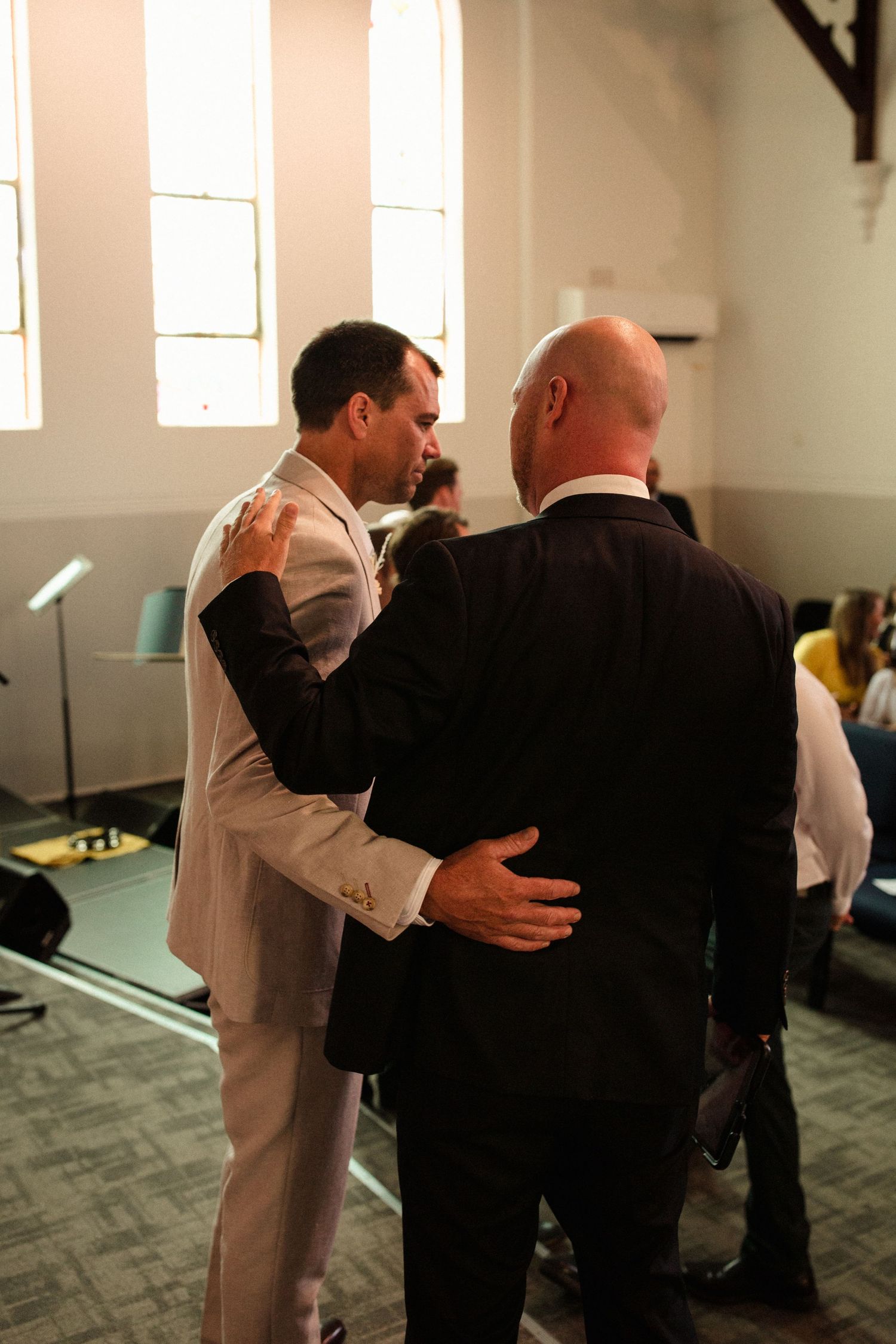 Two people sharing an emotional embrace in formal attire inside a church.