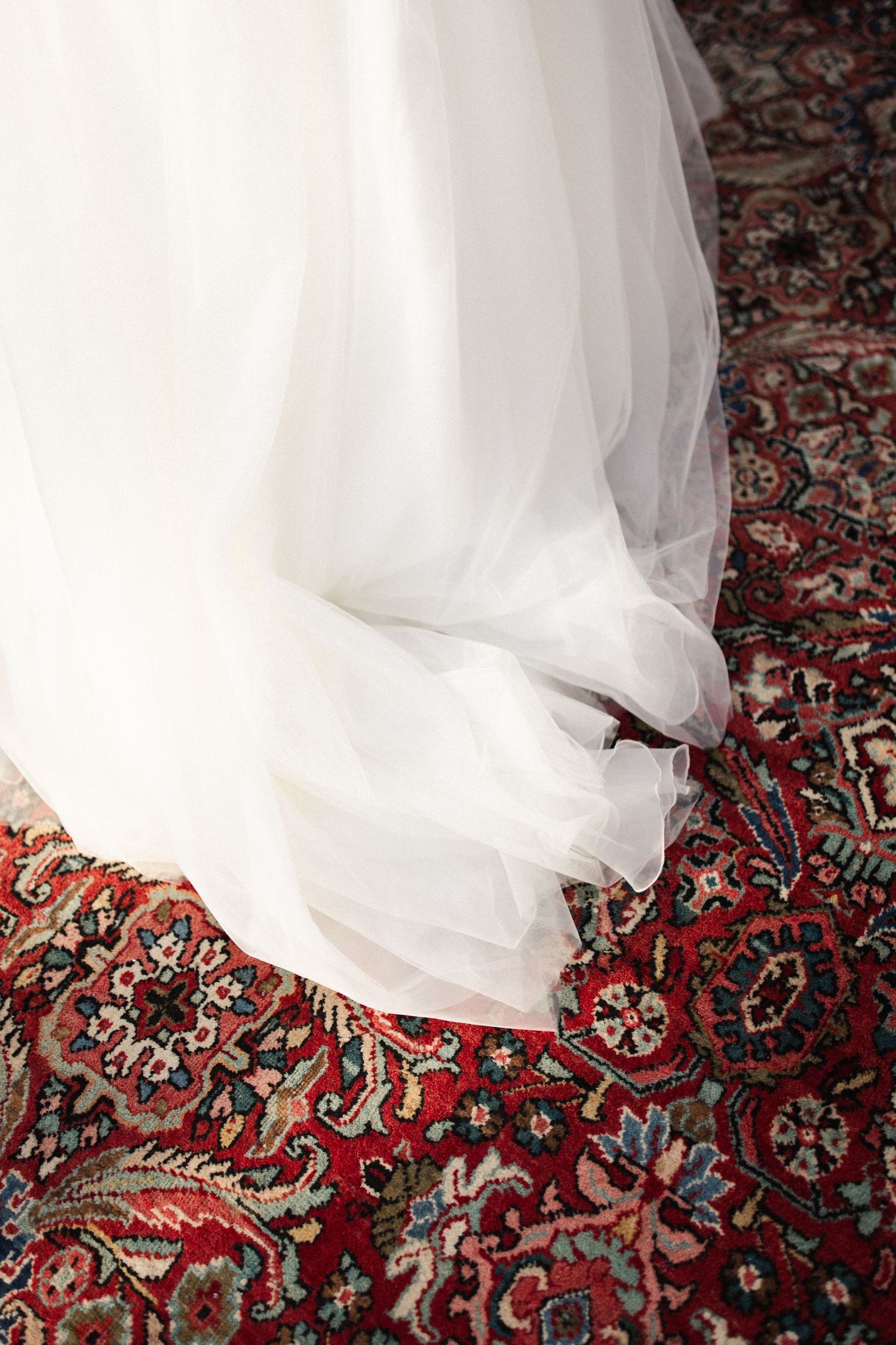Detailfoto van de trouwjurk en een kleurrijk vloerkleed.