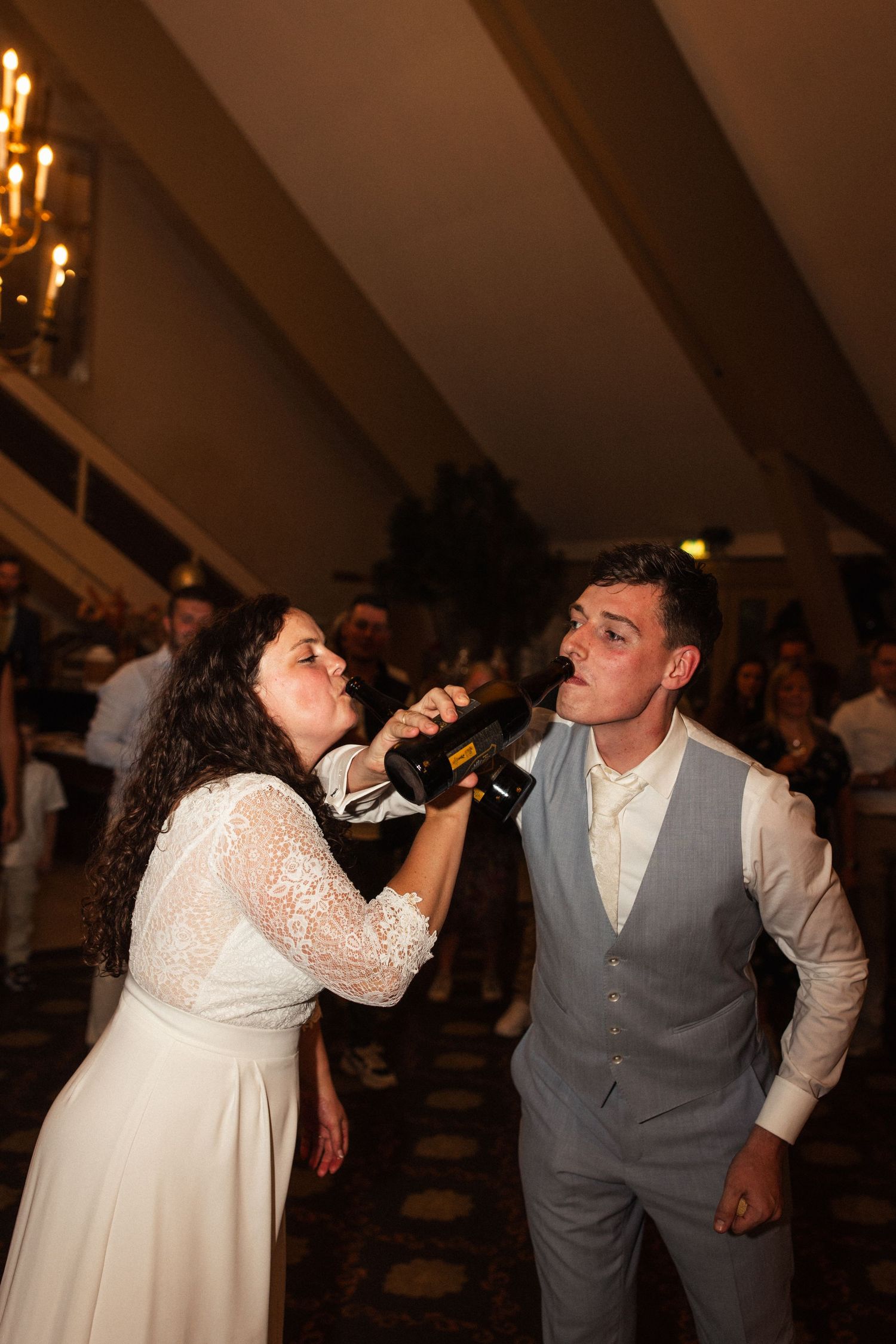 Newlyweds share a fun moment drinking beverages together during their wedding reception.