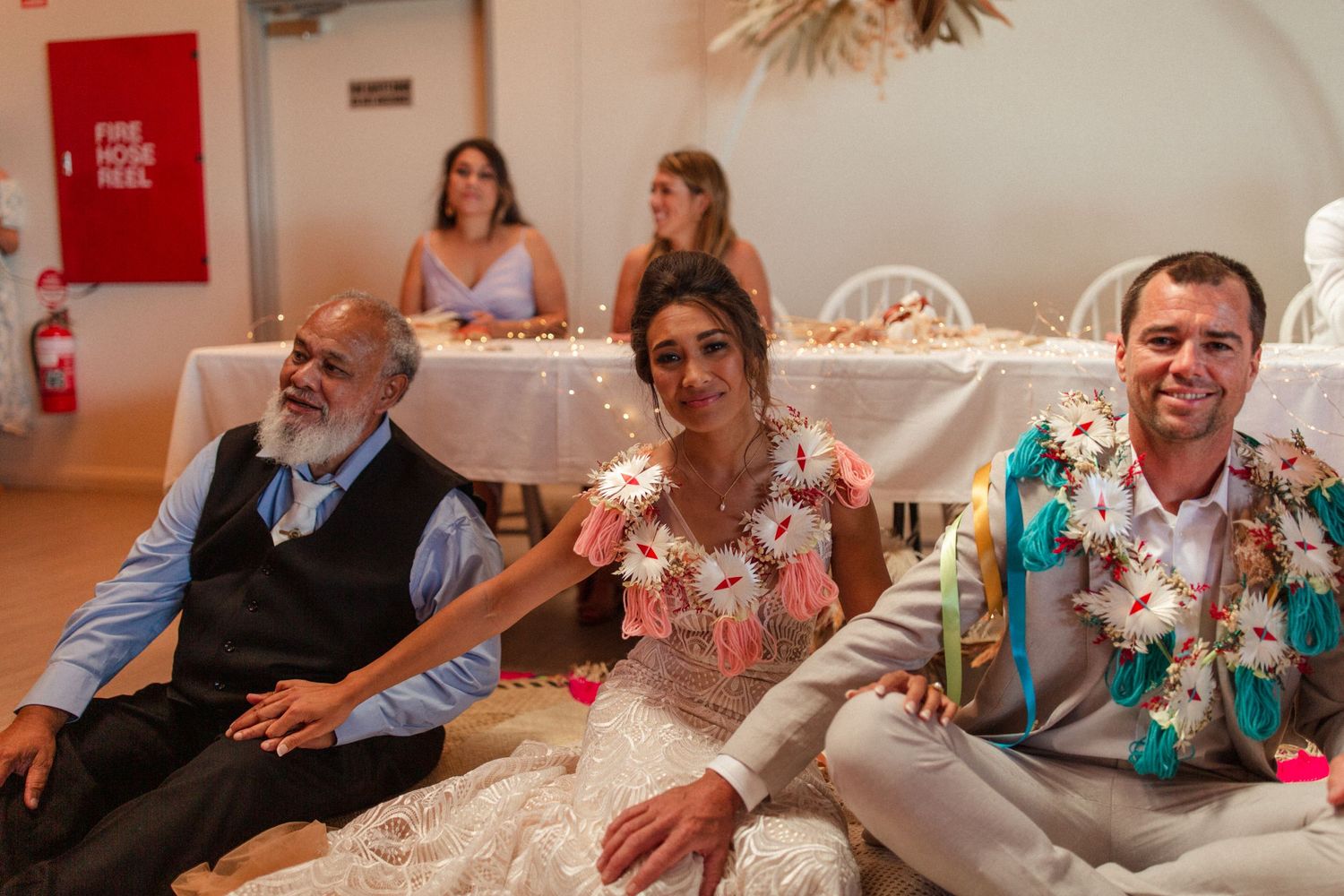 Guests enjoy a festive celebration with floral decorations and string lights overhead.