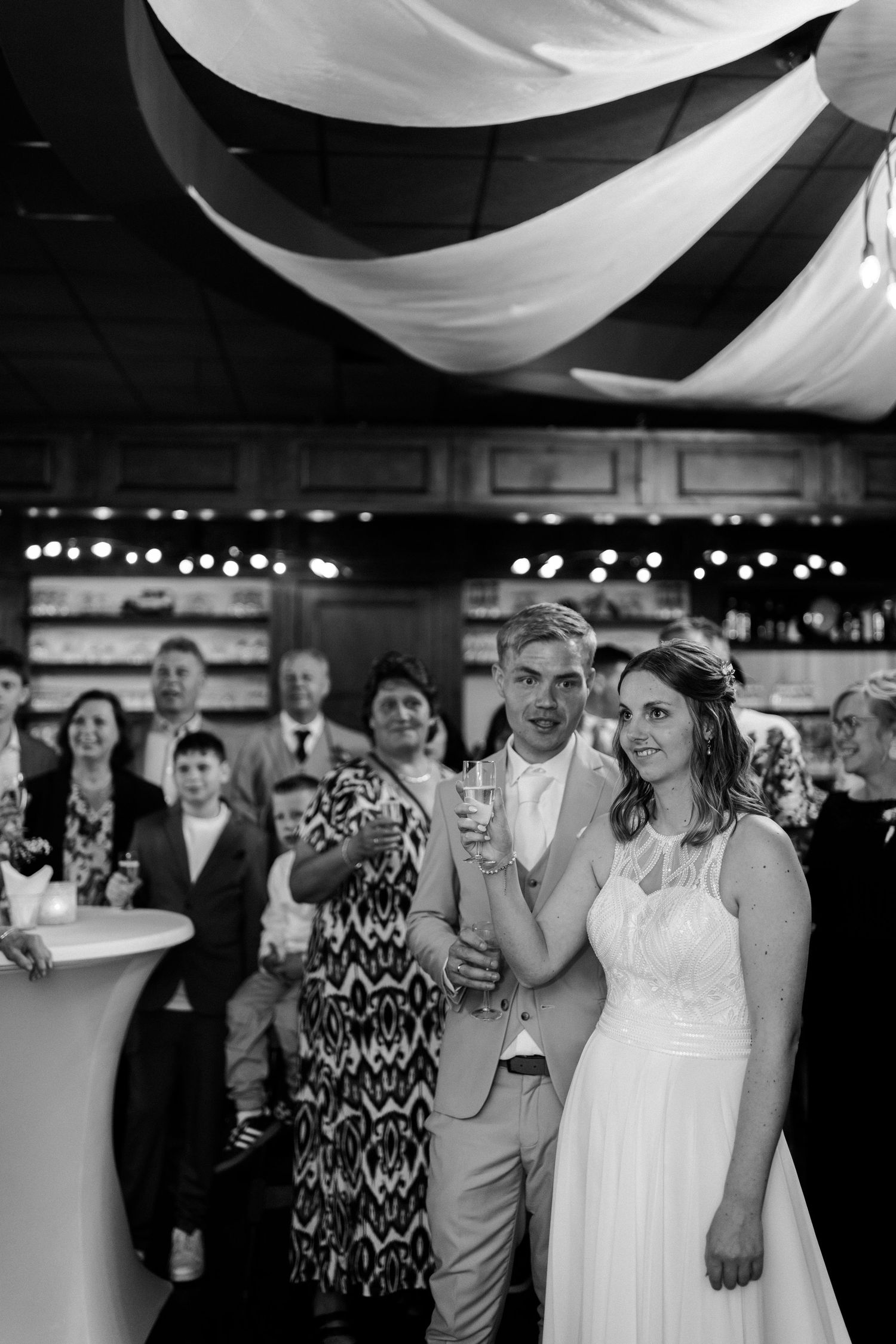 Black and white reception photo under draped fabric ceiling decorations.