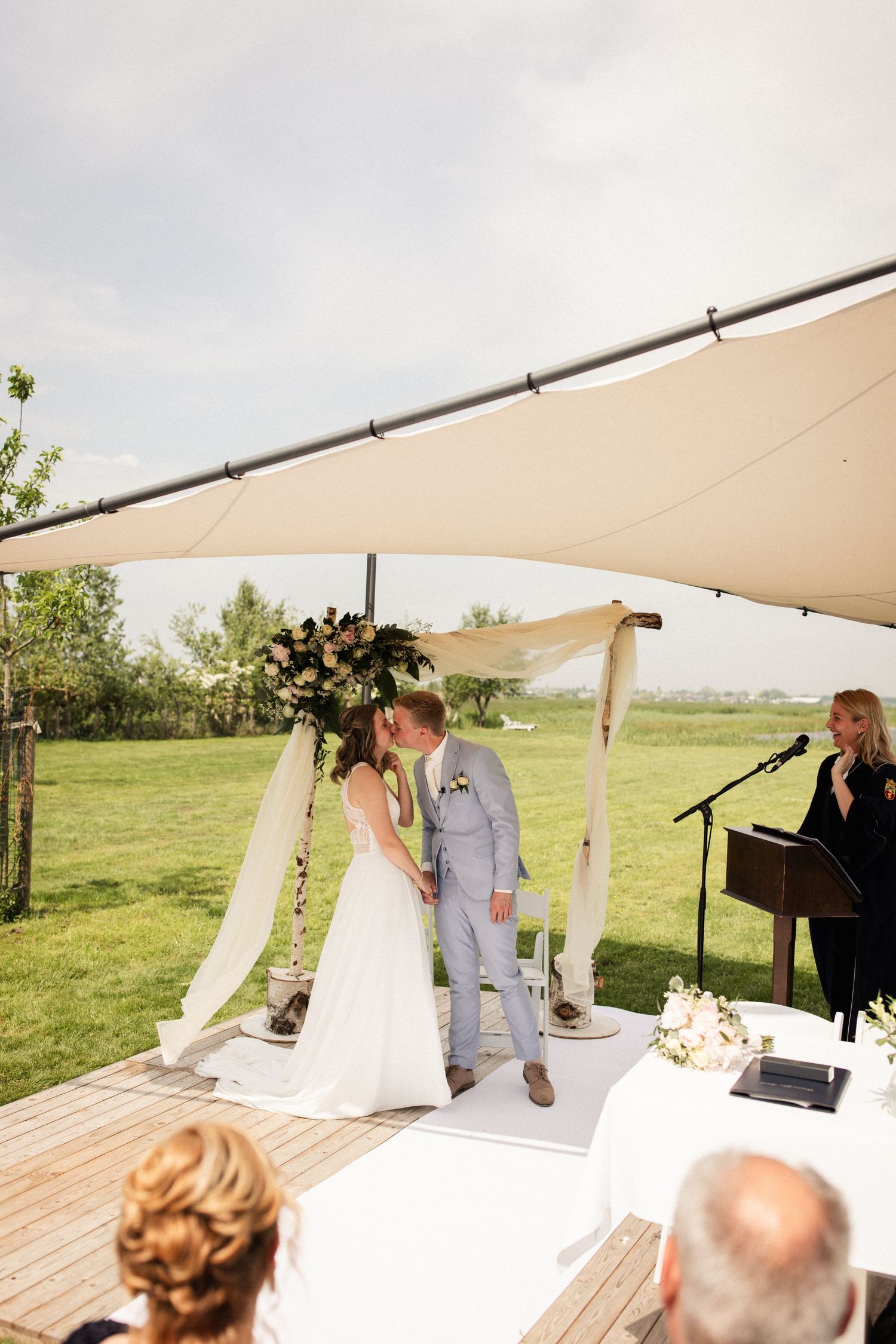 Wedding ceremony under a cream-colored canopy tent with pianist in background.