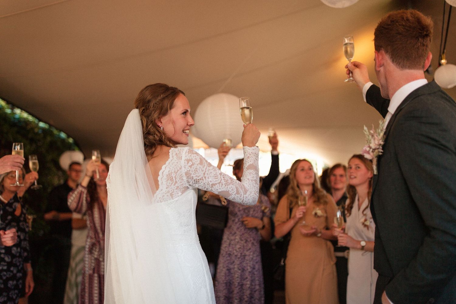 Wedding couple shares a fun moment dancing together on the dance floor with guests cheering in the background.