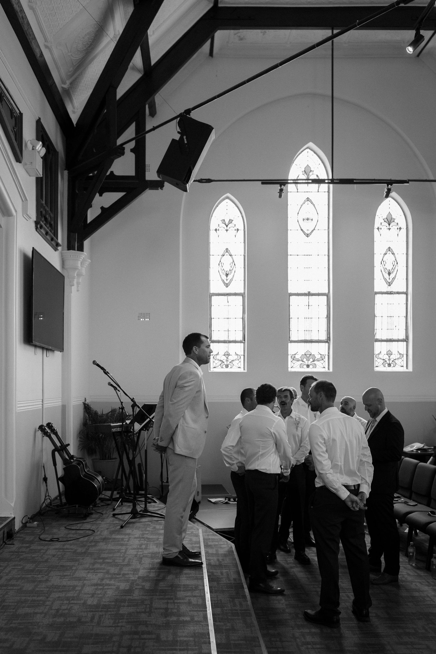 Black and white photo of a group gathered in a church with gothic windows.