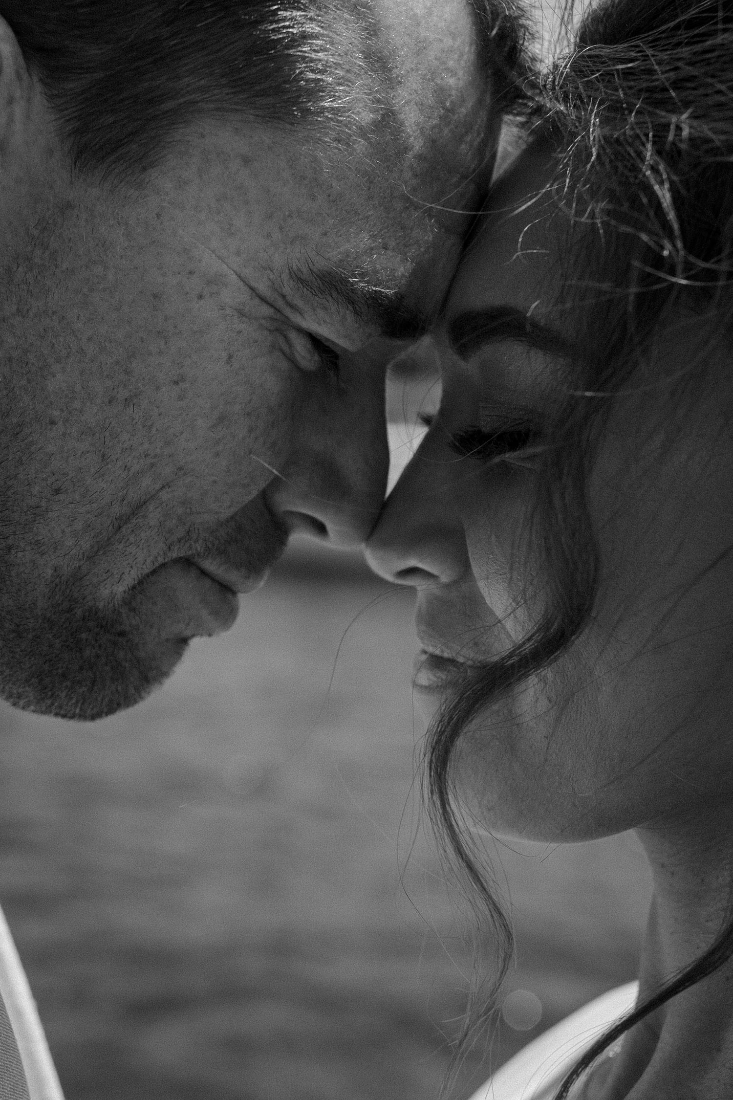 An intimate black and white close-up of a couple sharing a tender moment.