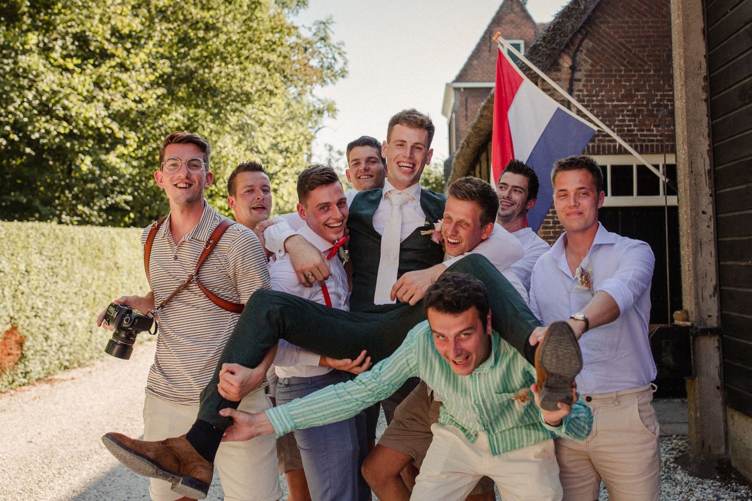 A group of friends pose playfully together outdoors on a sunny day, showing energetic and fun expressions.
