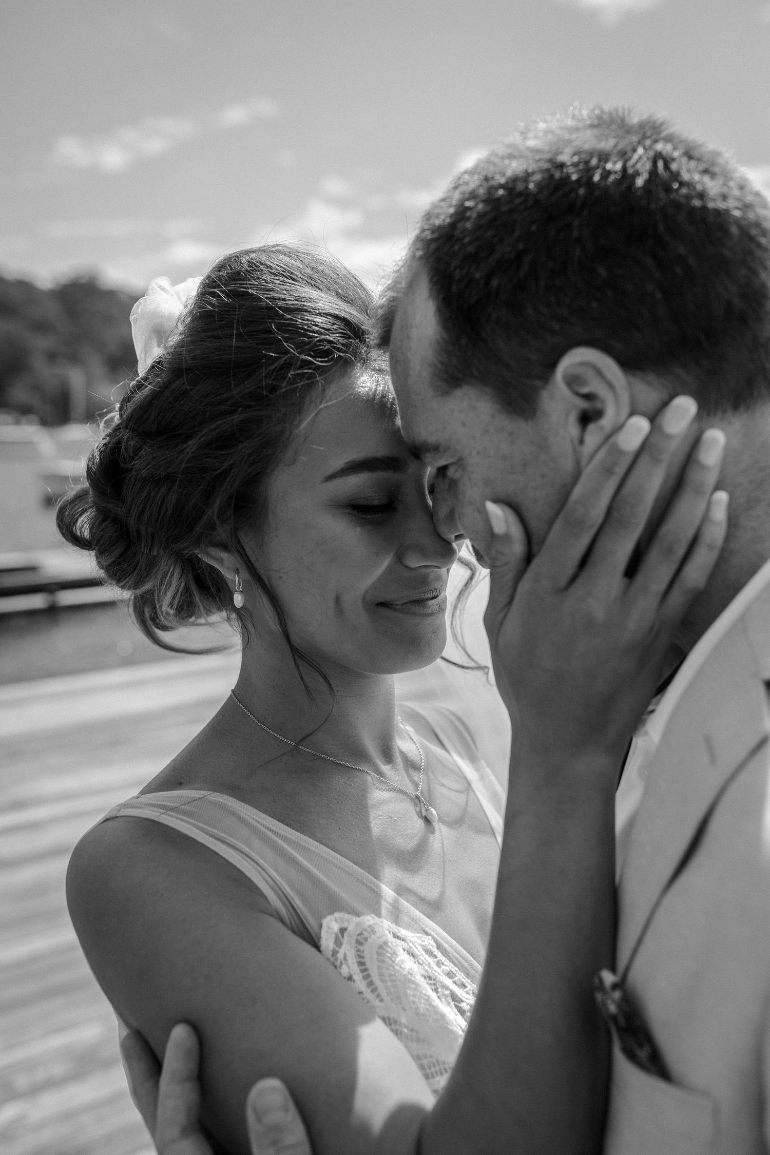 An intimate black and white portrait of newlyweds sharing a tender moment on their wedding day.