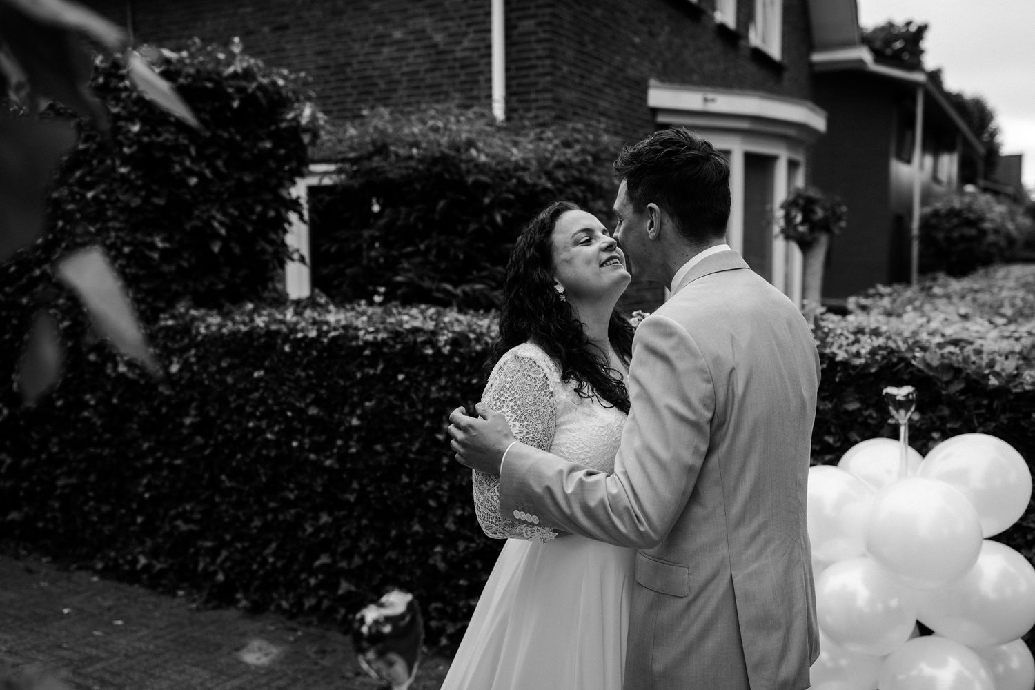 Black and white photo of couple celebrating with balloons in garden setting.